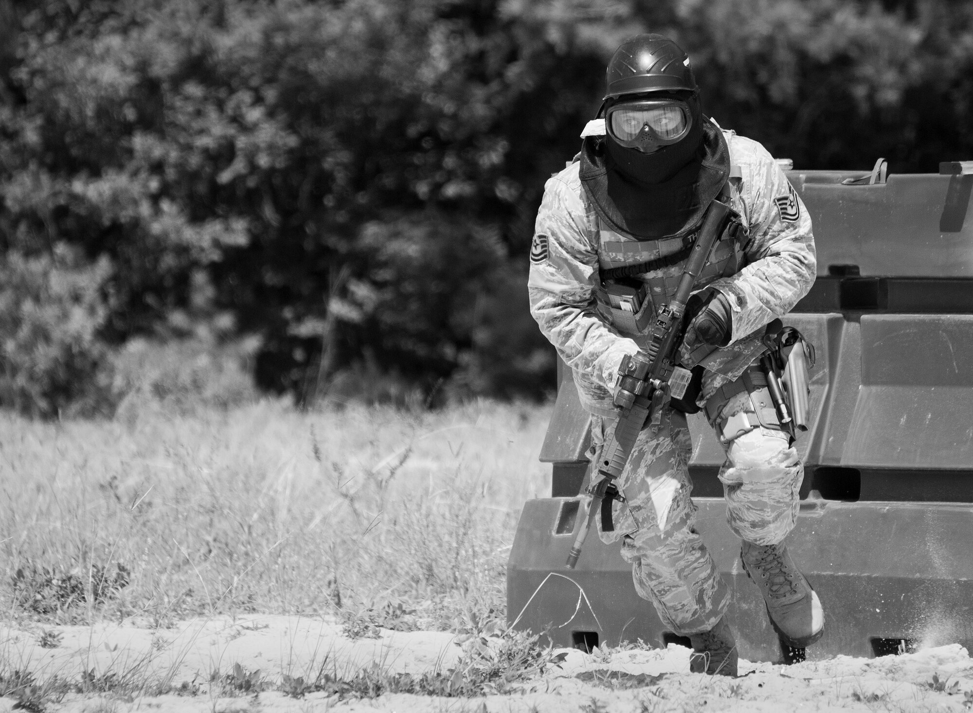 A 96th Security Forces Squadron Airman moves toward a barrier during a shoot, move and communicate drill in June at Eglin Air Force Base, Fla.  The mandatory training requirement is in addition to annual weapons qualification training.  The exercise consists of Airmen firing simmunition ammo while advancing toward, away from and to the side of a target.  This is followed by a building sweep and clear drill.  The Defenders perform the highly kinetic training at Eglin’s Base Tango range.  The range was previously used for security forces pre-deployment training.  (U.S. Air Force photo/Samuel King Jr.)