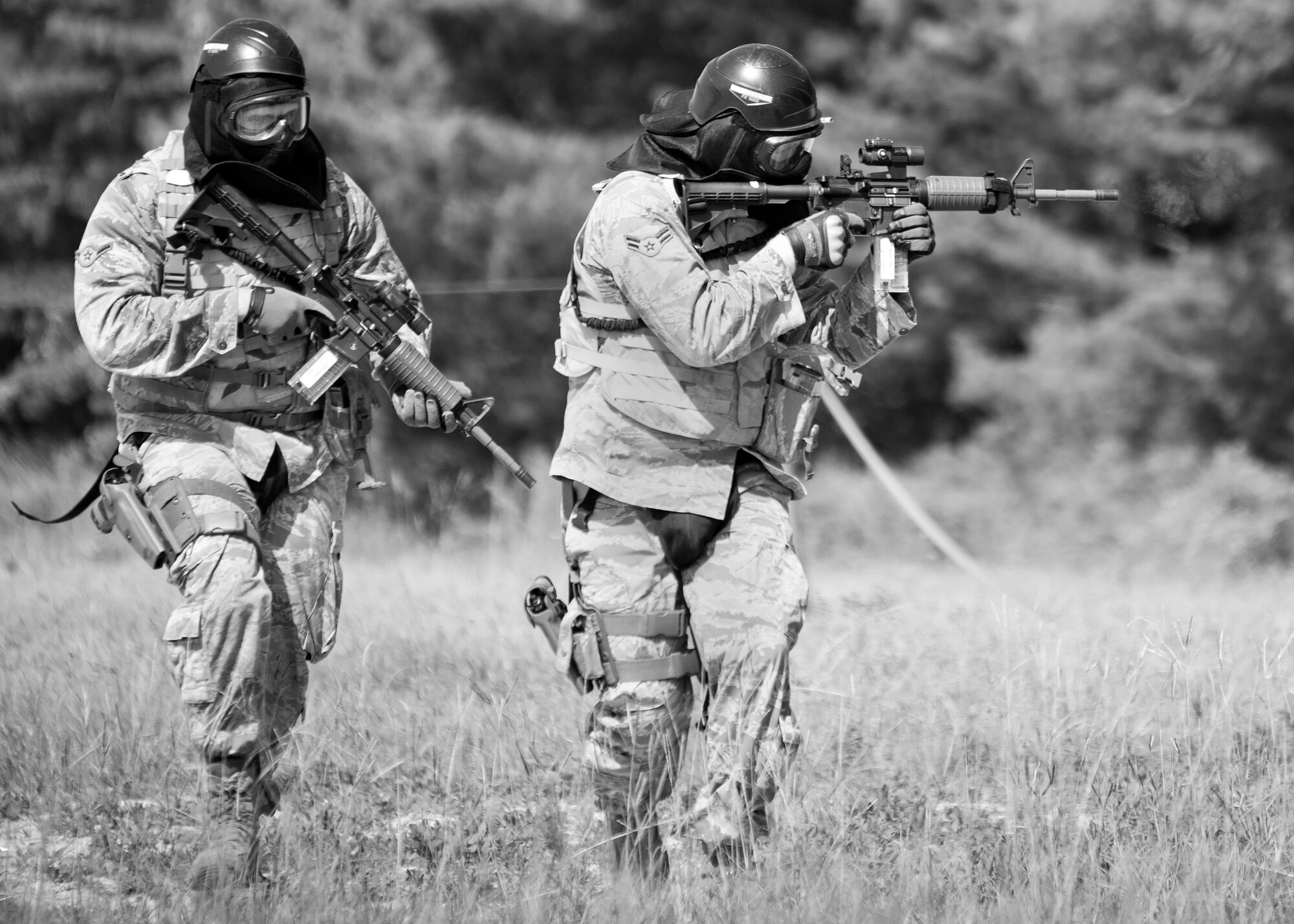 A two-person team of 96th Security Forces Squadron Airmen move toward a barrier during a shoot, move and communicate drill in June at Eglin Air Force Base, Fla.  The mandatory training requirement is in addition to annual weapons qualification training.  The exercise consists of Airmen firing simmunition ammo while advancing toward, away from and to the side of a target.  This is followed by a building sweep and clear drill.  The Defenders perform the highly kinetic training at Eglin’s Base Tango range.  The range was previously used for security forces pre-deployment training.  (U.S. Air Force photo/Samuel King Jr.)