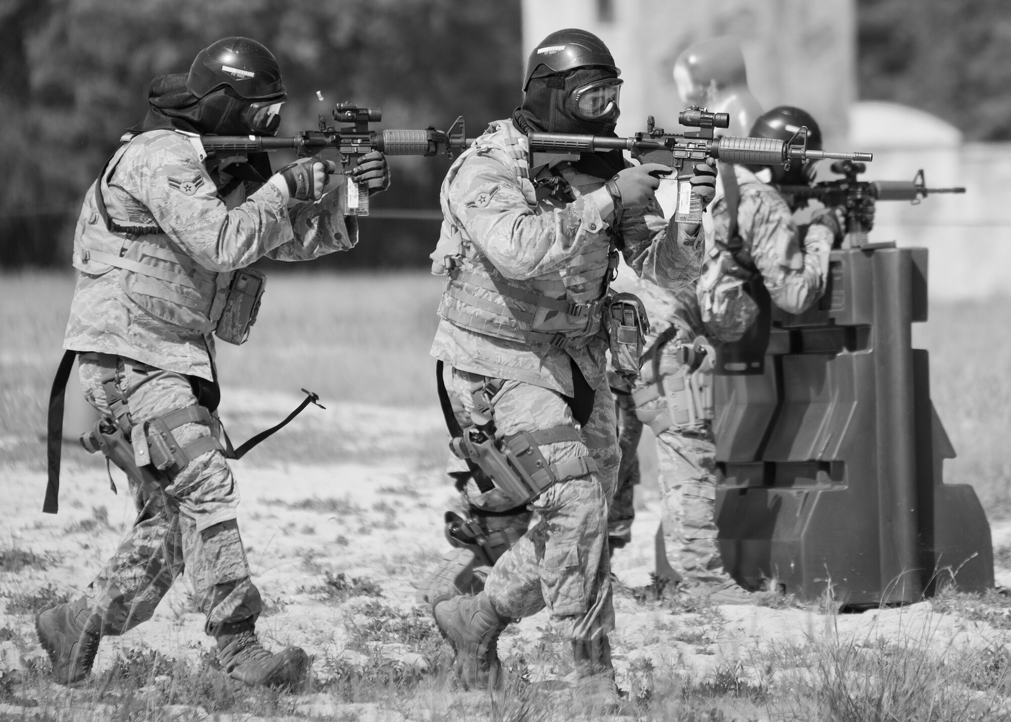 A pair of 96th Security Forces Squadron Airmen covers two more defenders as they advance forward during a shoot, move and communicate drill in June at Eglin Air Force Base, Fla.  The mandatory training requirement is in addition to annual weapons qualification training.  The exercise consists of Airmen firing simmunition ammo while advancing toward, away from and to the side of a target.  This is followed by a building sweep and clear drill.  The Defenders perform the highly kinetic training at Eglin’s Base Tango range.  The range was previously used for security forces pre-deployment training.  (U.S. Air Force photo/Samuel King Jr.)