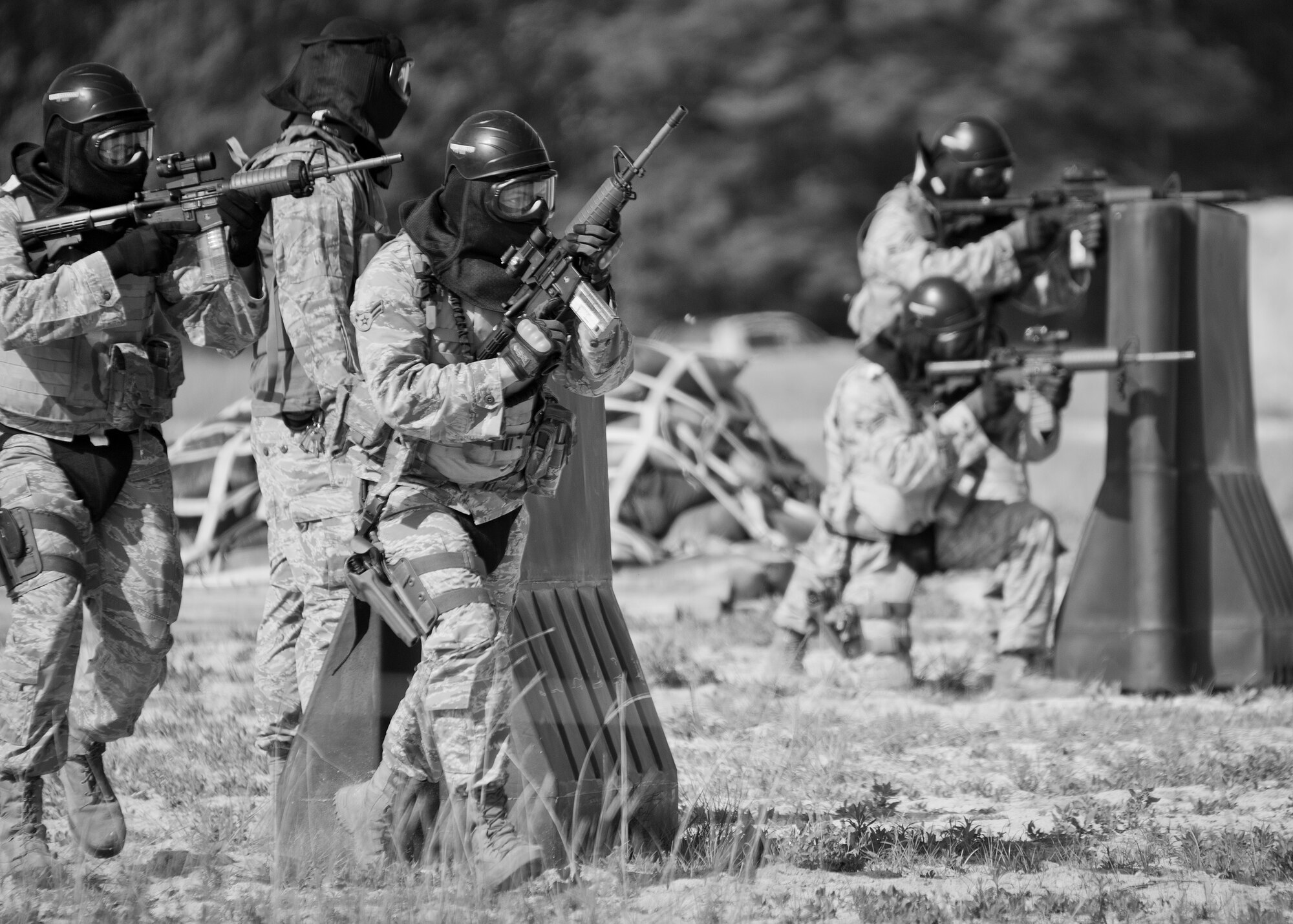 A pair of 96th Security Forces Squadron Airmen covers two more defenders as they advance forward during a shoot, move and communicate drill in June at Eglin Air Force Base, Fla.  The mandatory training requirement is in addition to annual weapons qualification training.  The exercise consists of Airmen firing simmunition ammo while advancing toward, away from and to the side of a target.  This is followed by a building sweep and clear drill.  The Defenders perform the highly kinetic training at Eglin’s Base Tango range.  The range was previously used for security forces pre-deployment training.  (U.S. Air Force photo/Samuel King Jr.)