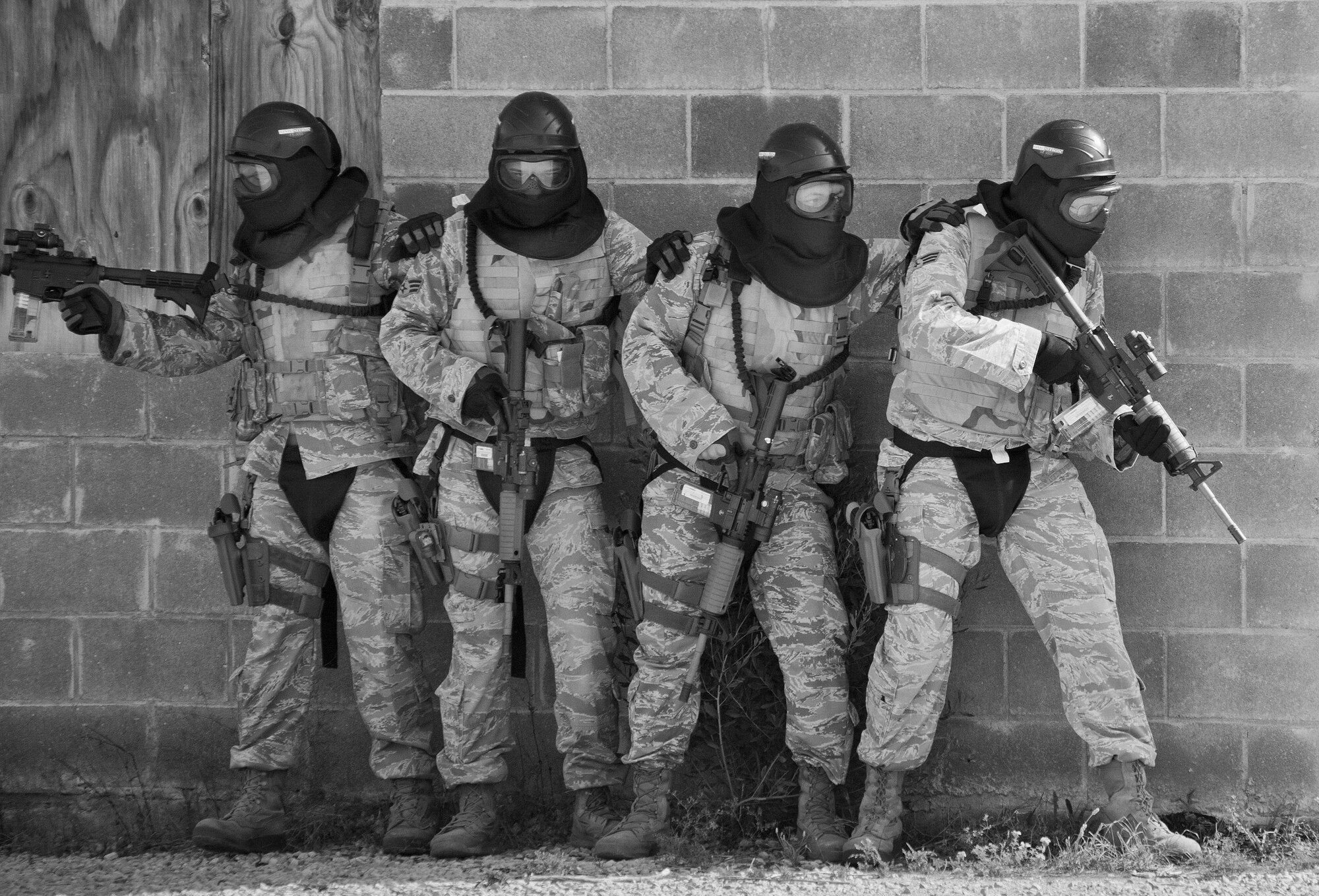 A team of 96th Security Forces Squadron Airmen prepare to enter a building during a shoot, move and communicate drill in June at Eglin Air Force Base, Fla.  The mandatory training requirement is in addition to annual weapons qualification training.  The exercise consists of Airmen firing simmunition ammo while advancing toward, away from and to the side of a target.  This is followed by a building sweep and clear drill.  The Defenders perform the highly kinetic training at Eglin’s Base Tango range.  The range was previously used for security forces pre-deployment training.  (U.S. Air Force photo/Samuel King Jr.)