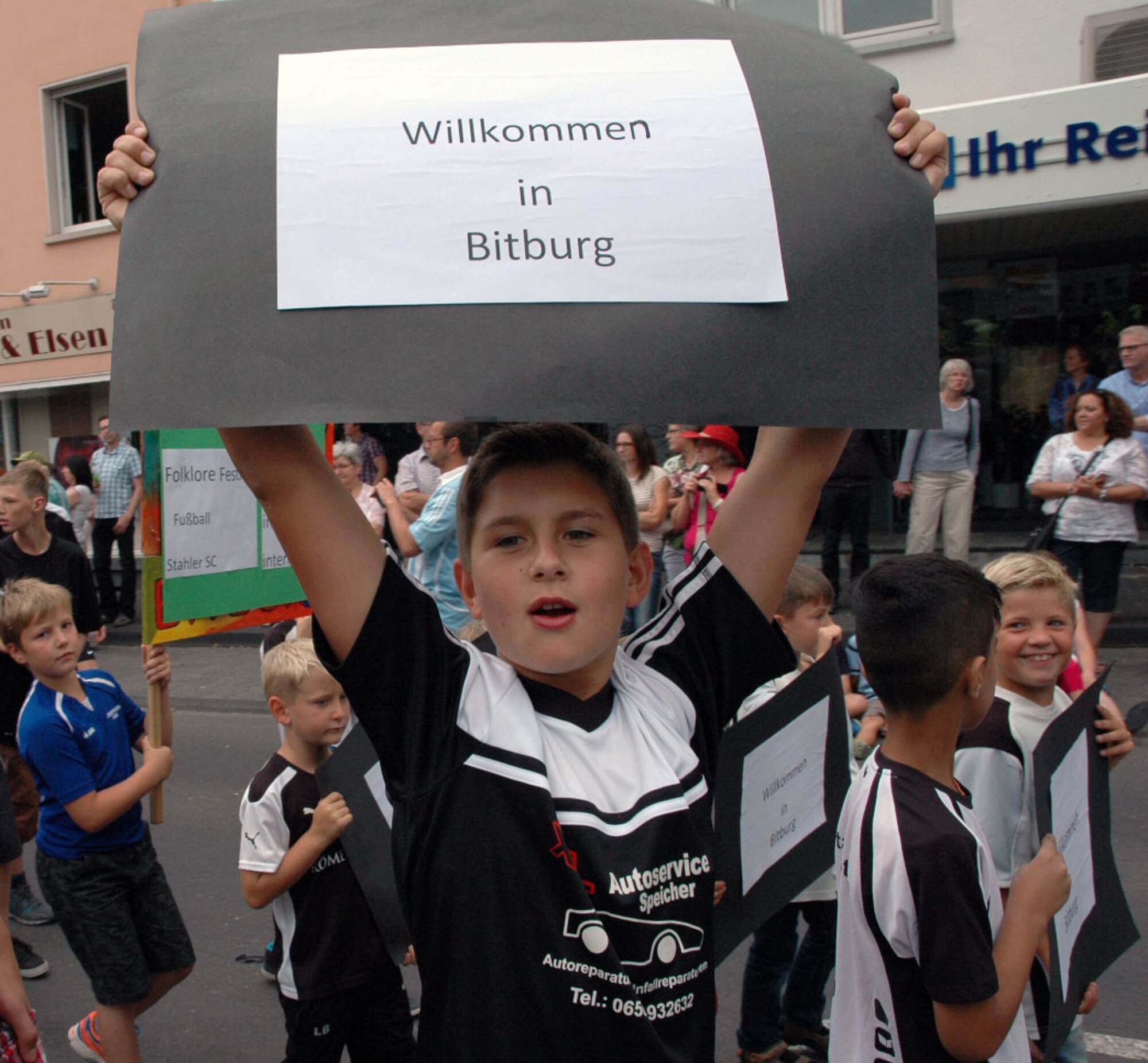 A German boy holds up a sign as he walks through the streets with other members of his club during the City of Bitburg's Folklore festival in Bitburg, Germany, July 12, 2015. Observers participated in the events in commemoration of the city's 1,300th anniversary and the Folk Festival's 50th anniversary. (U.S. Air Force photo by Iris Reiff/Released)