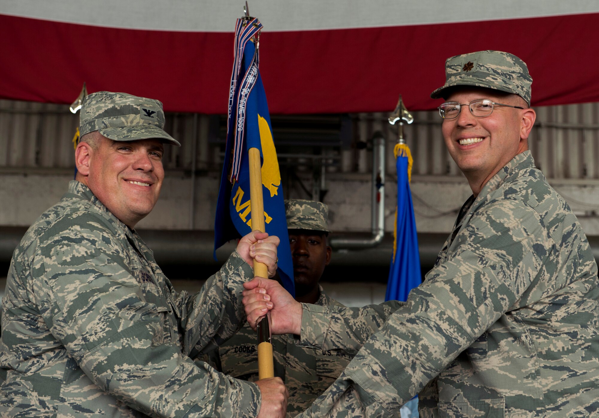 U.S. Air Force Col. Stephen Scherzer, 52nd Maintenance Group commander, left, passes the ceremonial guidon to U.S. Air Force Maj. David Marce, incoming 52nd Equipment Maintenance Squadron commander, during the 52nd Equipment Maintenance Squadron change of command ceremony in Hangar 2 on Spangdahlem Air Base, Germany, July 17, 2015. The 52nd EMS provides safe, reliable, and world-class aircraft, equipment, and munitions maintenance to the 52nd Fighter Wing in support of U.S. Air Forces in Europe and Africa and NATO objectives. (U.S. Air Force photo by Airman 1st Class Timothy Kim/Released)