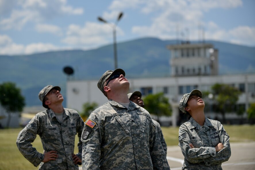 Airmen and Soldiers watch as paratroopers parachute over Krumuvo Air Base, Bulgaria, July 16, 2015. The airdrop was a part of an air show that showcased not only personnel drops, but also emergency medical evacuation procedures. The U.S. is committed to supporting Bulgaria’s continued integration into NATO as an important member of the alliance. (U.S. Air Force photo/Senior Airman Nicole Sikorski)