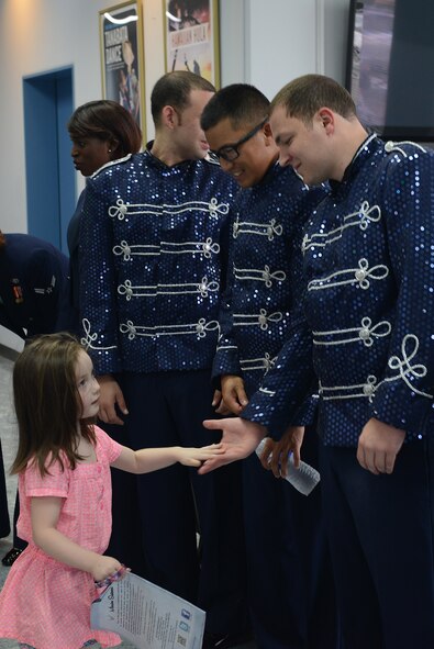 A child high-fives musicians after a Tops in Blue performance at Yokota Air Base, Japan, July 19, 2015. Tops in Blue promotes community relations, support recruiting efforts and serve as ambassadors for the U.S. and the Air Force when performing overseas. (U.S. Air Force photo by Airman 1st Class David C. Danford/Released)