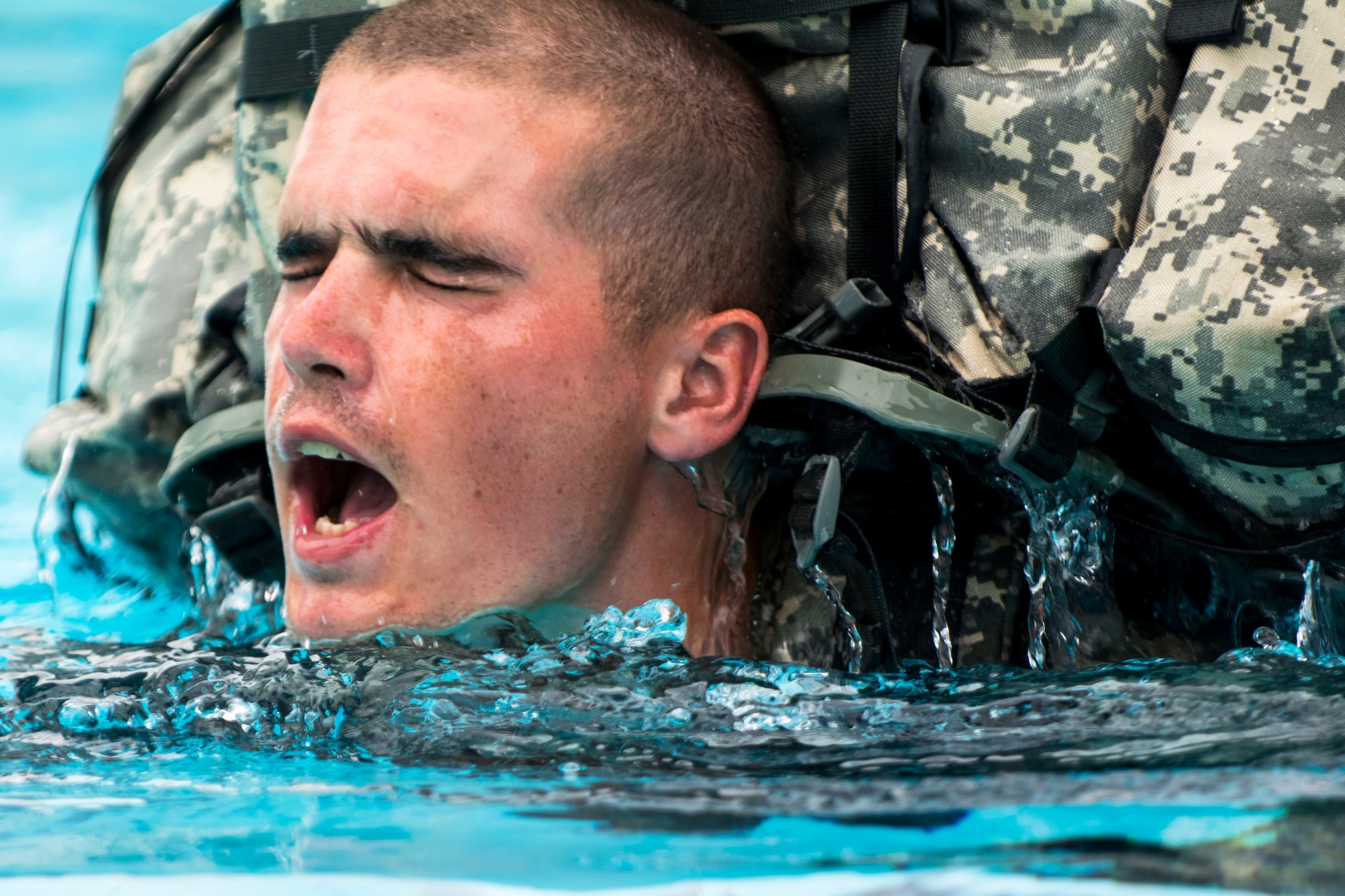 A soldier takes a breather while swimming 25 meters with a ruck sack and a dummy weapon during combat water survival training at Fort Hunter Liggett, Calif., July 17, 2015.