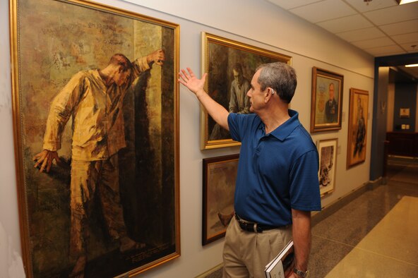 Retired Col. Leon Ellis visits the Air Force prisoner of war tribute section in the Pentagon July 16, 2015. Ellis, a Vietnam War POW, admired a painting by Maxine McCaffrey. The painting portrays realistic features about being a captive in a prison camp. (U.S. Air Force photo/Staff Sgt. Whitney Stanfield)