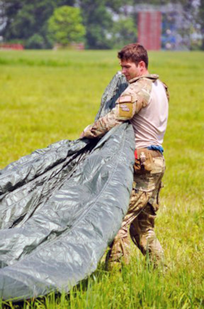Air Force Staff Sgt. Travis Brown, a pararescueman with the Kentucky Air National Guard's 123rd Special Tactics Squadron, helps another parachutist collect his gear before the next round of jumpers exit a C-130 cargo airplane, June 8, 2011, during the Precision Rescue Jumpmaster Course conducted at Camp Atterbury, Ind. Students and instructors dropped into the drop zone two at a time and had to clear the field before the next C-130 pass over.