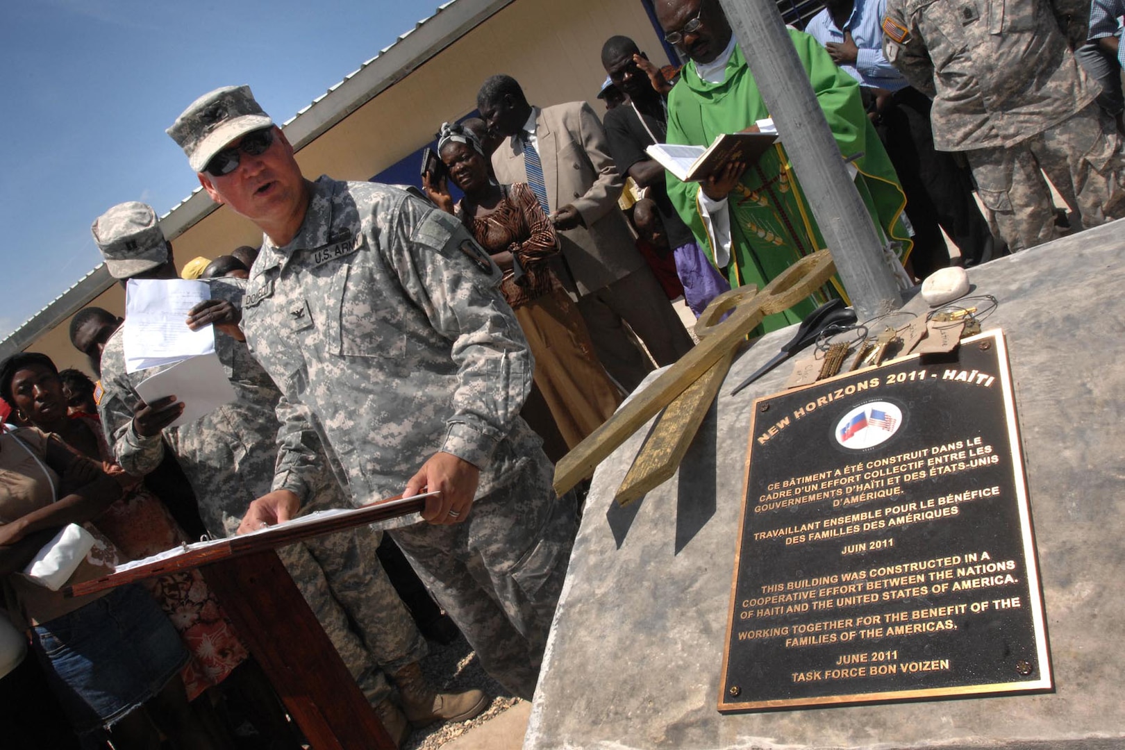 Army Col. Kenneth Donnelly, commander of Task Force Bon Voizen and a Louisiana National Guard member, turns over the keys of a new school and medical clinic to the residents of Upper Poteau, Haiti, June 20, 2011. The school and clinic were two of the engineer projects built in Haiti by troops of Task Force Bon Voizen.