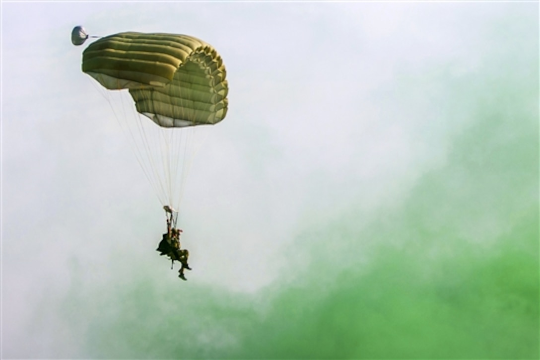 A U.S. airman parachutes to the ground during high-altitude, low-opening jump training at Bagram Airfield, Afghanistan, July 18, 2015. Green smoke marks the drop zone to guide the pararescuemen to their landing point. The airman is a pararescueman assigned to the 83rd Expeditionary Rescue Squadron, which has a mission to rescue, recover and return American or allied forces in times of danger or extreme duress.