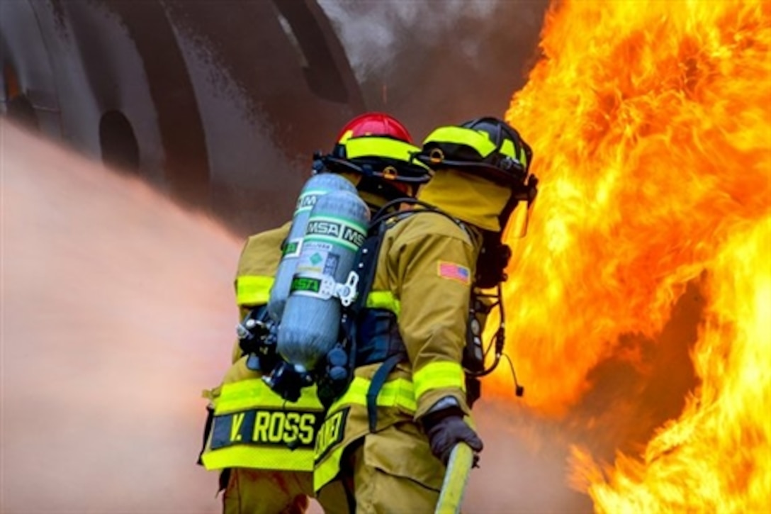 Firefighters spray water during an aircraft rescue and fire burn as they prepare for the annual Patriot Exercise at Volk Field Combat Readiness Training Center, Wis., July 16, 2015. National Guard units conduct the domestic disaster-response training exercise with federal, state and local emergency management agencies and first responders. The firefighters are assigned to the 181st and the 317th Engineer detachments, Nebraska Army National Guard. 