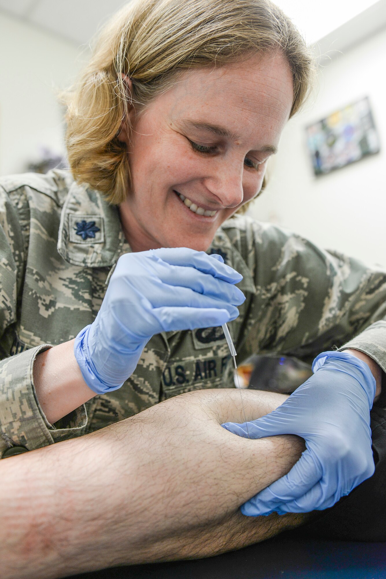 Lt. Col. Linda Currier, 374th Surgical Operations Squadron surgical services flight commander, inserts acupuncture needles into her patient’s calf muscle at Yokota Air Base, Japan, June 30, 2015. Currier said that acupuncture is an effective way to relieve pain and tension, helping Airmen perform their duties with a healthier mind and body. (U.S. Air Force photo by Airman 1st Class Elizabeth Baker/Released)
