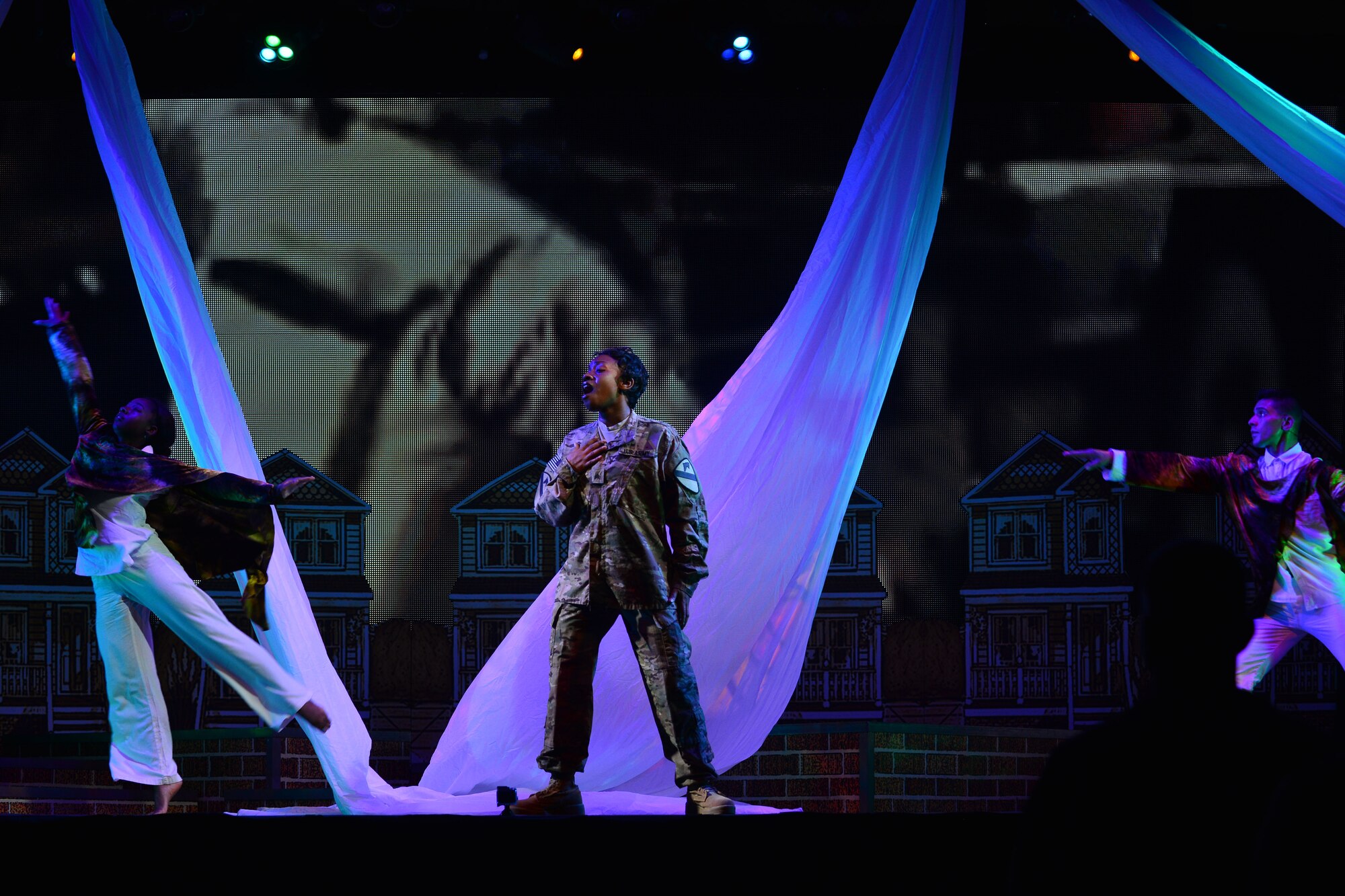 U.S. Army Sgt. Neasha Powell, U.S. Army Morale, Welfare and Recreation Programs Soldier Show performer, sings between interpretive dancers during a performance at Fort Eustis, Va., July 15, 2015. Fort Eustis Soldiers and their families, as well as Advanced Individual Training students, and Gold Star Family members attended the show. (U.S. Air Force photo by Staff Sgt. Natasha Stannard/Released)