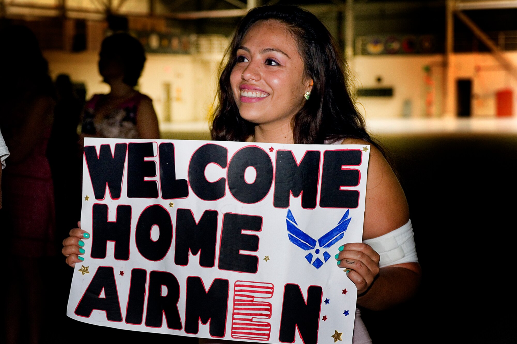 Yvette Morales, girlfriend of Senior Airman Manuel Parades, 434th Security Forces fire team member, holds a sign to greet returning Airmen at Grissom Air Reserve Base, Ind., July 21, 2015. Families and friends gathered during the pre-dawn hours to welcome 30 defenders home from a 180-day deployment to Southwest Asia. (U.S. Air Force photo/Tech. Sgt. Douglas Hays)