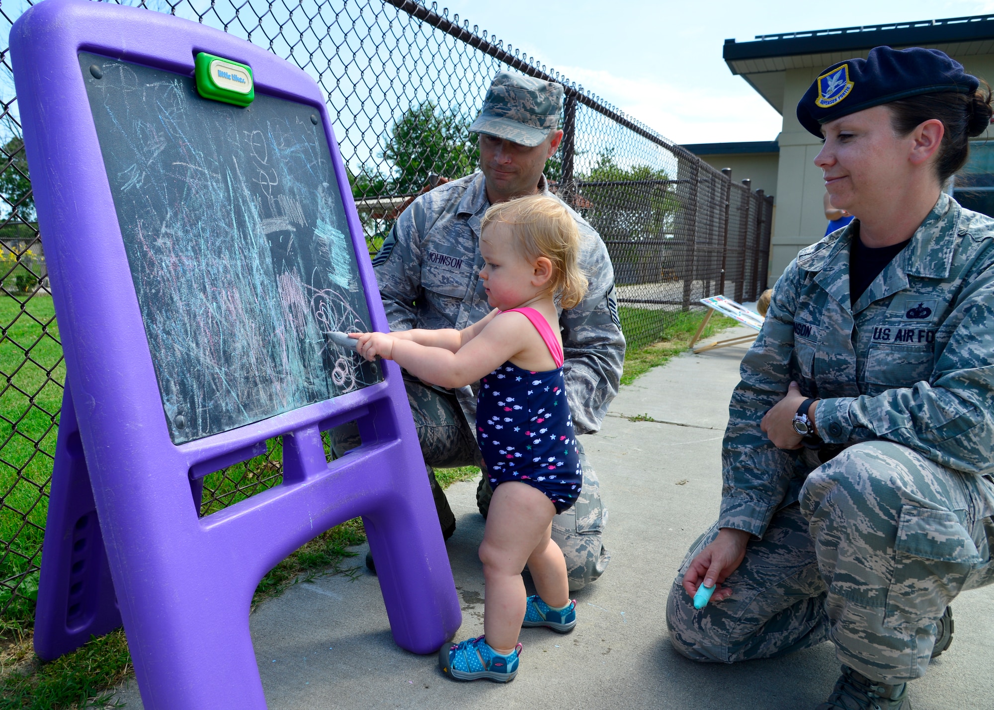 Tech. Sgt. Jessica Johnson, 436th Security Forces Squadron kennel master, and Master Sgt. Eric Johnson, 736th Aircraft Maintenance Squadron first sergeant, watch their daughter, Jaylynn Johnson, color on a chalk board during Pre Toddler Fun Day July 17, 2015, at the Child Development Center on Dover Air Force Base, Del. Various water and outdoor activities were available during the day on the pre toddler playground and the event wrapped up Pre Toddler Spirit Week at the CDC. (U.S. Air Force photo/Airman 1st Class William Johnson) 