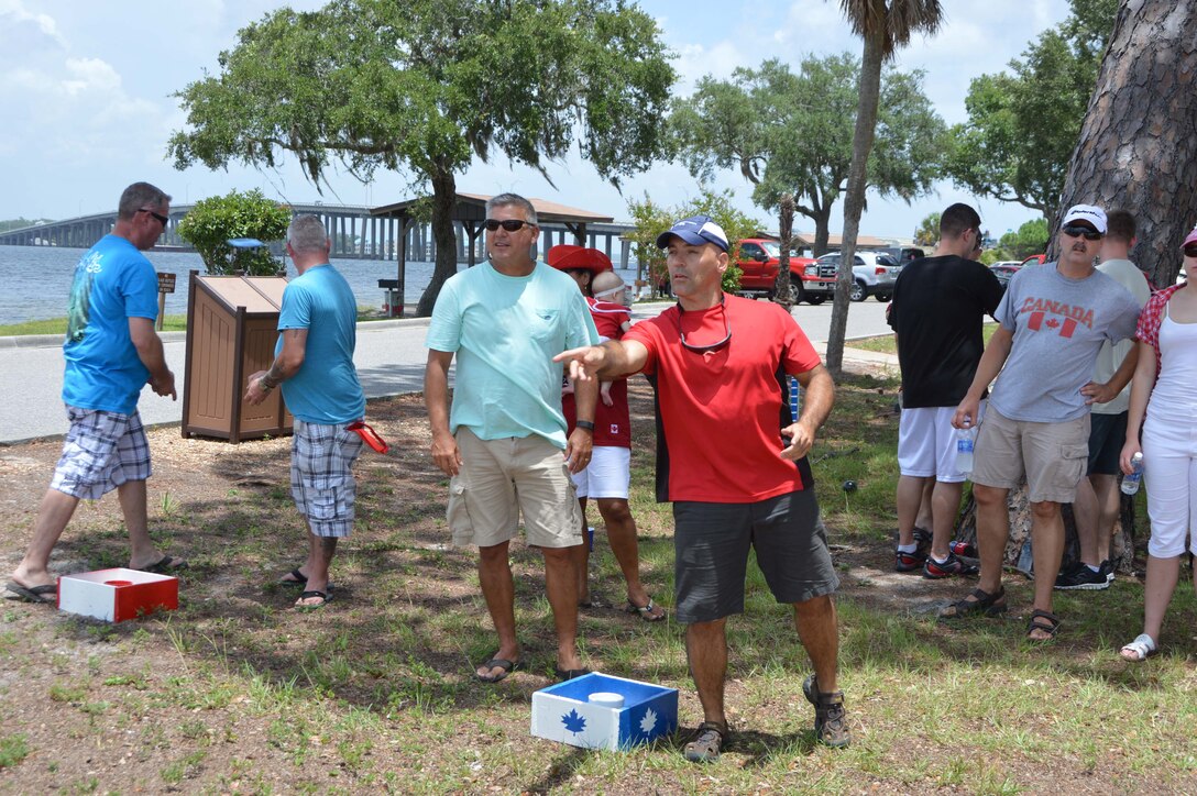 (Left) Master Sgt. Rex Barrentine, 101st Air Communications Squadron, watches Royal Canadian Air Forces Maj. Daniel Ceniccola, 101st ACOMS, toss a washer during Canada Day festivities at Bonita Bay July 1.  Members of the Canadian Detachment assigned to Headquarters Continental U.S. North American Aerospace Defense Region – 1st Air Force (Air Forces Northern) celebrated the day that recognizes Canada’s independence from the British Empire in 1867 by hosting an afternoon of food and games. (Air Force Photo Released/Maj. Kat Andrews)