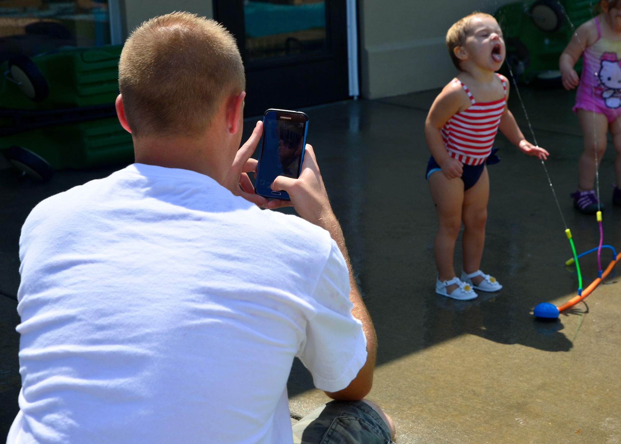 Airman 1st Class Tannor Foulger, 436th Aerial Port Squadron ramp operations, takes a picture of his daughter, Mila Foulger, during the Pre Toddler Fun Day July 17, 2015, at the Child Development Center on Dover Air Force Base, Del. Seven different activities and stations were part of the fun day for pre toddlers and parents to enjoy together. (U.S. Air Force photo/Airman 1st Class William Johnson)