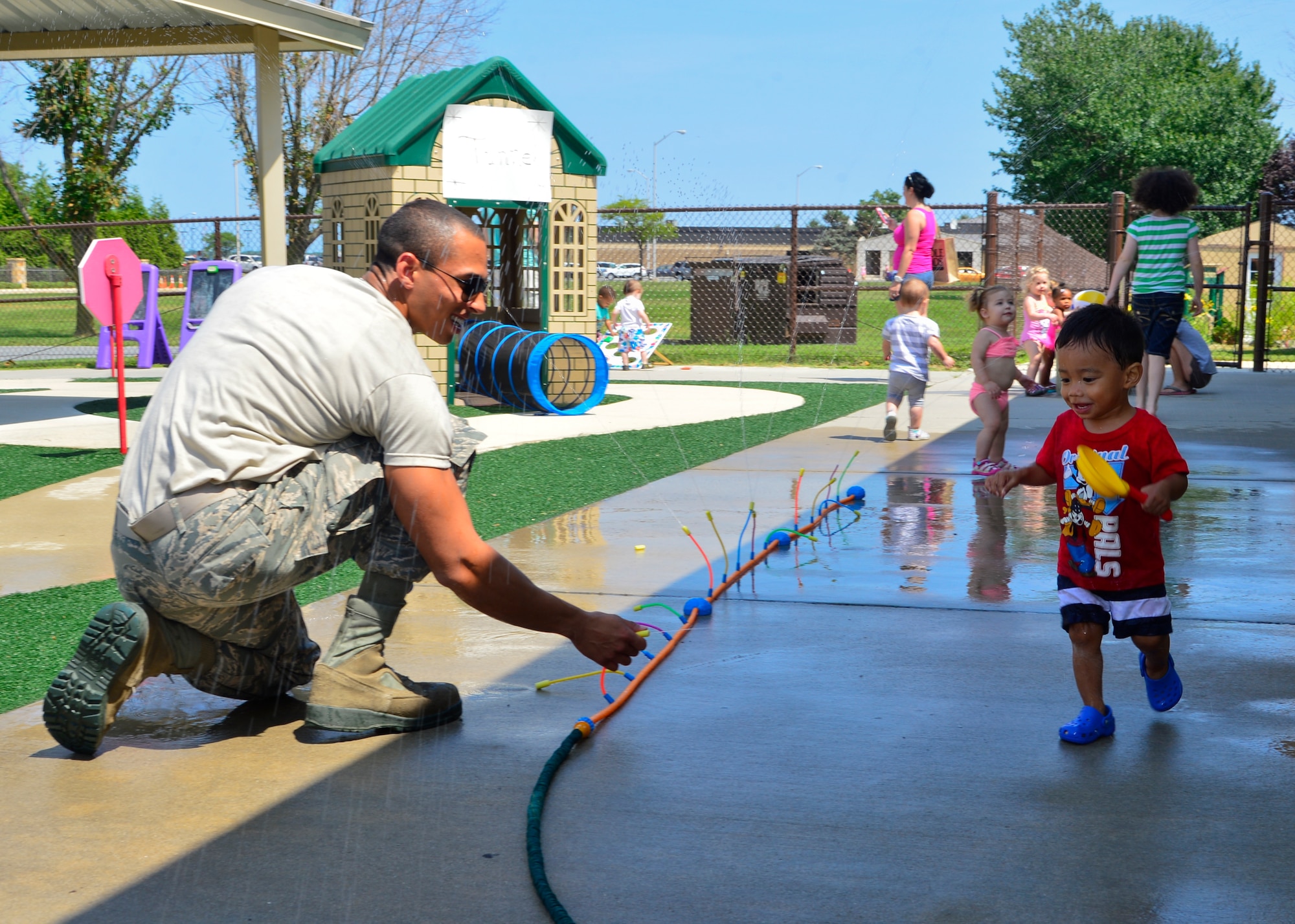 Senior Airman Brandon Clayton, 436th Logistic Readiness Squadron supply, sprays his son, Brayden Clayton, with a water hose during Pre Toddler Fun Day July 17, 2015, at the Child Development Center on Dover Air Force Base, Del. The Pre Toddler Fun Day was the last day in the Pre Toddler Spirit Week that had different themes and activities for each day of the week. (U.S. Air Force photo/Airman 1st Class William Johnson)