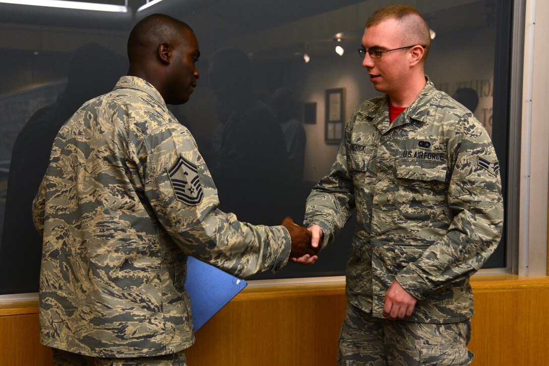 U.S. Air Force Senior Master Sgt. Ralph Oliver, 633rd Civil Engineer Squadron first sergeant, presents a challenge coin to Airman 1st Class Jake Hendrick, 633rd CES administrative specialist, for receiving a Diamond Sharp award at Langley Air Force Base, Va., July 17, 2015. Hendrick earned the quarterly first sergeants’ award by being an avid volunteer and exceptional worker, according to Oliver. (U.S. Air Force photo by Senior Airman Aubrey White/Released)
