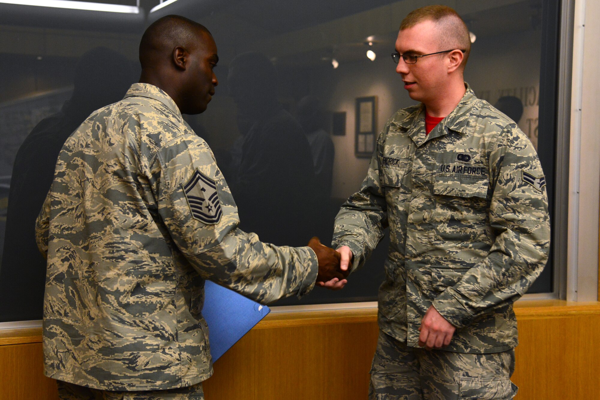 U.S. Air Force Senior Master Sgt. Ralph Oliver, 633rd Civil Engineer Squadron first sergeant, presents a challenge coin to Airman 1st Class Jake Hendrick, 633rd CES administrative specialist, for receiving a Diamond Sharp award at Langley Air Force Base, Va., July 17, 2015. Hendrick earned the quarterly first sergeants’ award by being an avid volunteer and exceptional worker, according to Oliver. (U.S. Air Force photo by Senior Airman Aubrey White/Released)