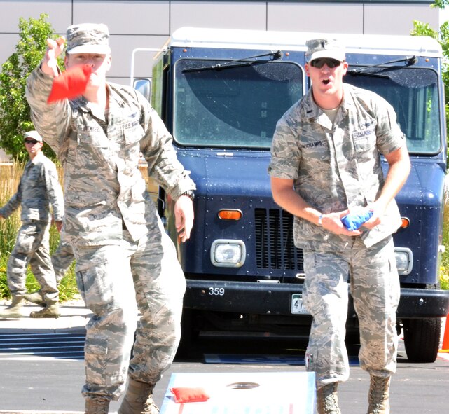 Airman 1st Class Brandon Myers, 2nd Space Operations Squadron, throws a bean bag while 1st Lt. Kyle Longchamps, 2 SOPS, looks on Friday, July 17, 2015 during a game of cornhole at Schriever Air Force Base, Colorado. The game was just one of the events available during the annual Summer Slam Base Picnic hosted by the 50th Force Support Squadron. (U.S. Air Force photo/Brian Hagberg)