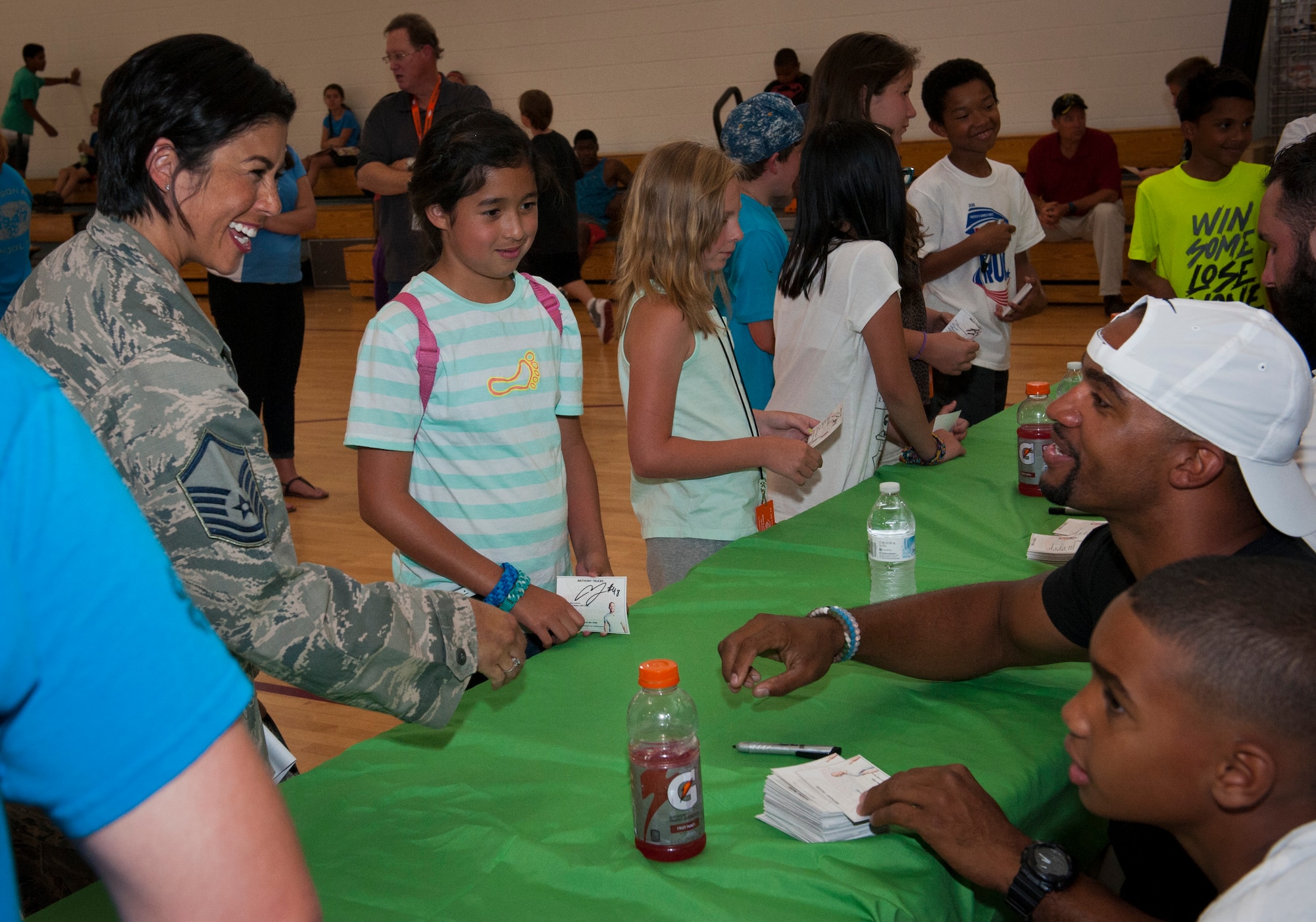 PETERSON AIR FORCE BASE, Colo. – Master Sgt. Karmann Pogue, U.S. Northern Command contingency operations superintendent, and her daughter Ava talk with Anthony Trucks, former linebacker for the Pittsburgh Steelers, as they get his autograph at the R.P. Lee Youth Center, July 13, 2015. Trucks was one of three professional football players at Peterson to give advice to youth about sports and life in general. (U.S. Air Force photo by Airman 1st Class Rose Gudex)