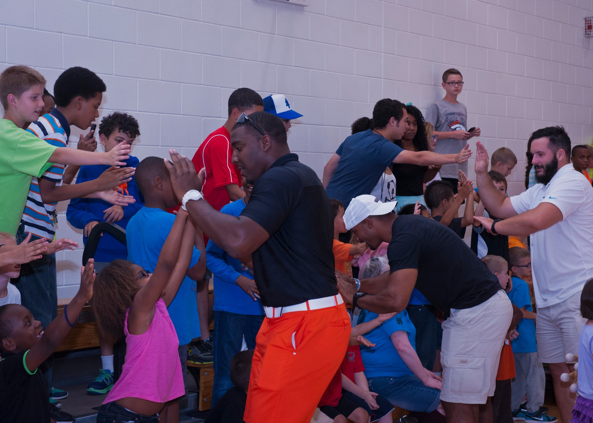 PETERSON AIR FORCE BASE, Colo. – Three professional football players greet excited kids before talking with them for the Pro Football Camp at the R.P. Lee Youth Center, July 13, 2015. The players giving advice were (from left) Greg Scruggs, Seattle Seahawks defensive end; Anthony Trucks, former Pittsburgh Steelers linebacker, and Brian Folkert, center for the Carolina Panthers. The camp started 10 years ago as a way to give back to the community and encourage kids to do their best in everything they do. (U.S. Air Force photo by Airman 1st Class Rose Gudex)