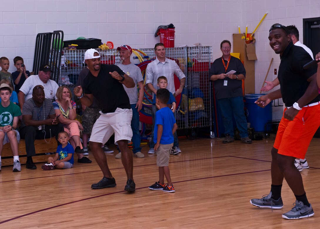 PETERSON AIR FORCE BASE, Colo. – Anthony Trucks (left), former Pittsburgh Steelers linebacker, and Greg Scruggs (right), Seattle Seahawks defensive end, dance with kids as they prepare to give a presentation about their football careers and the importance of hard work and dedication at the R.P. Lee Youth Center, July 13, 2015. They were at Peterson for the Pro Football Camp, a nonprofit organization that uses football to give back to the community and encourage youth. (U.S. Air Force photo by Airman 1st Class Rose Gudex)