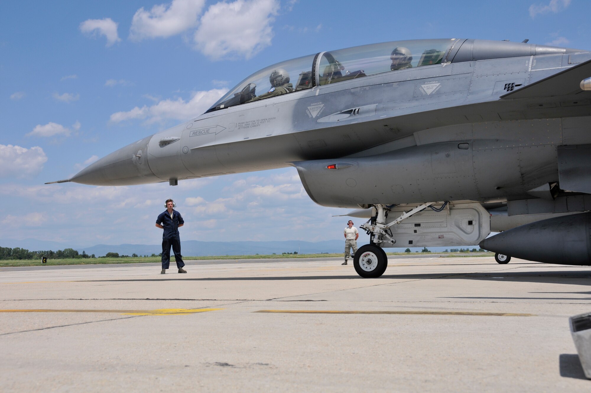 A picture of U.S. Air Force Senior Airmen Christian Mirande and George Ruczynski, crew chiefs, standing ready to marshall F-16C and D model Fighting Falcons prior to takeoff.