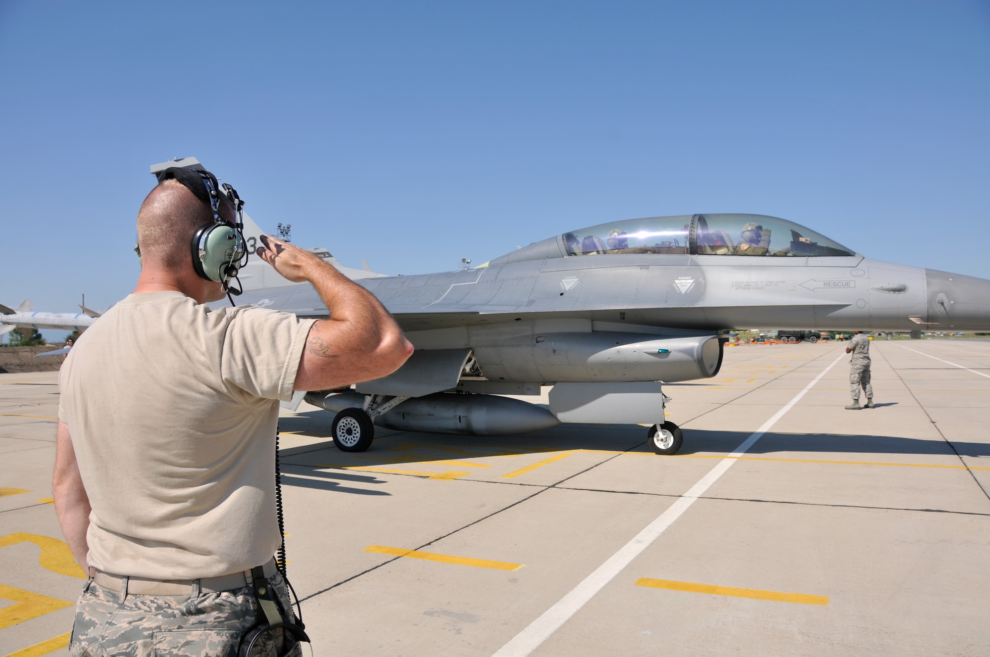 A picture of U.S. Air Force Senior Airman Mark Cavanaugh, crew chief with the 177th Fighter Wing of the New Jersey Air National Guard, saluting a pilot in a U.S. Air Force F-16D Fighting Falcon.