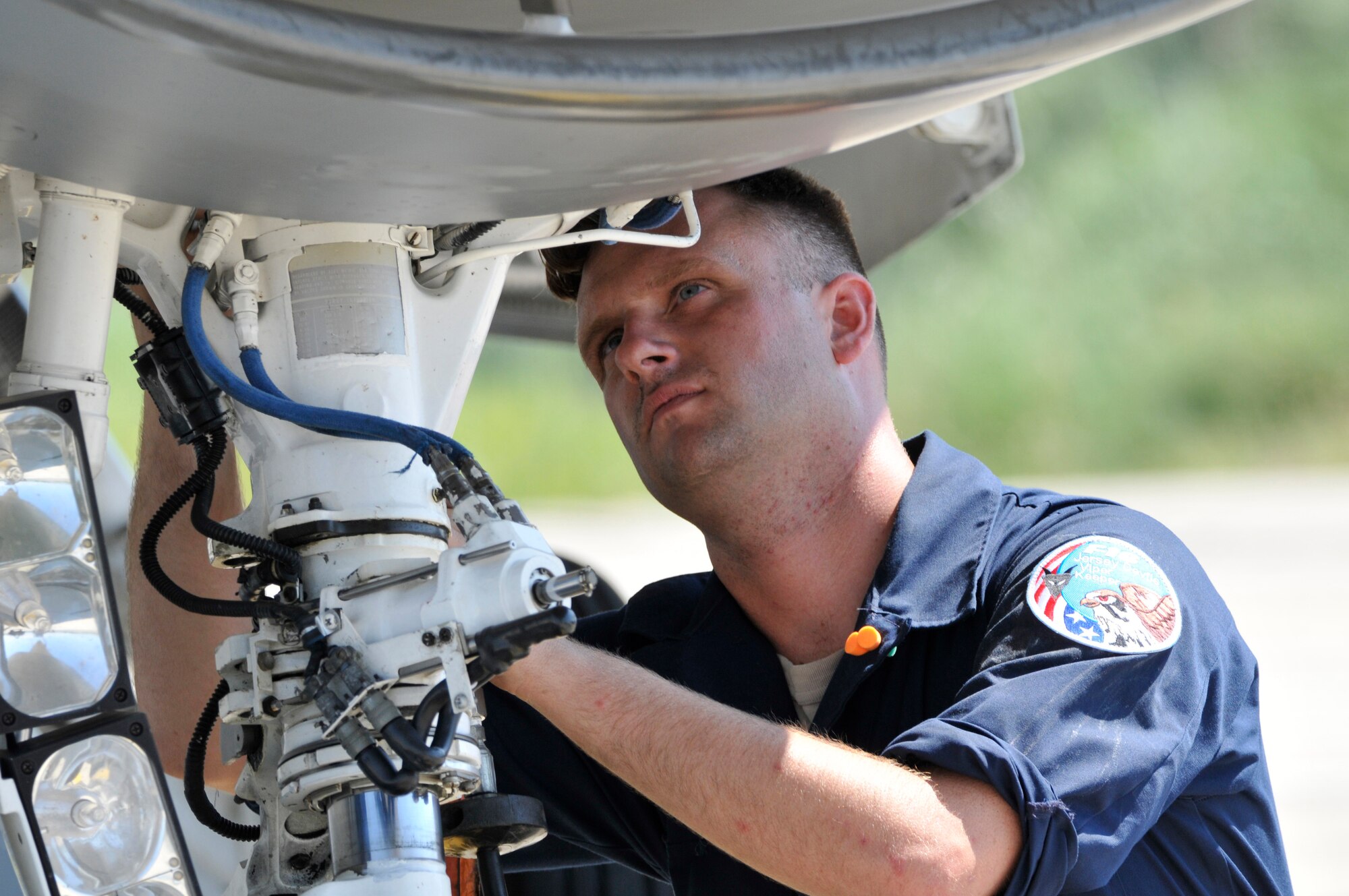 A picture of U.S. Air Force Senior Airman Christian Mirande, crew chief, performing a strut servicing in conjunction with his basic post flight inspection on an F-16D Fighting Falcon.