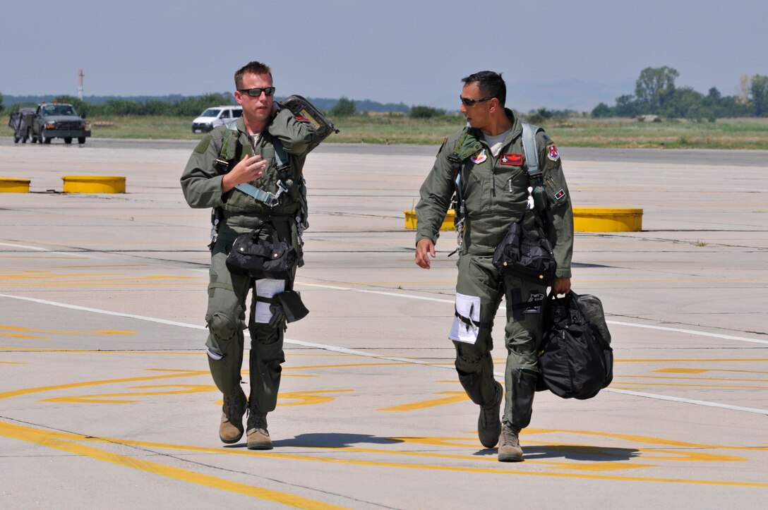 U.S. Air Force Lt. Col. Philippe Malebranche, right, and Maj. Benjamin Robbins, F-16 pilots with the 177th Fighter Wing, walk to their post-flight briefing after a training mission during Thracian Star, a bilateral training exercise to enhance interoperability with the Bulgarian air force, at Graf Ignatievo Air Base, Bulgaria, on July 13, 2015. (U.S. Air National Guard photo by Master Sgt. Andrew J. Moseley/Released)