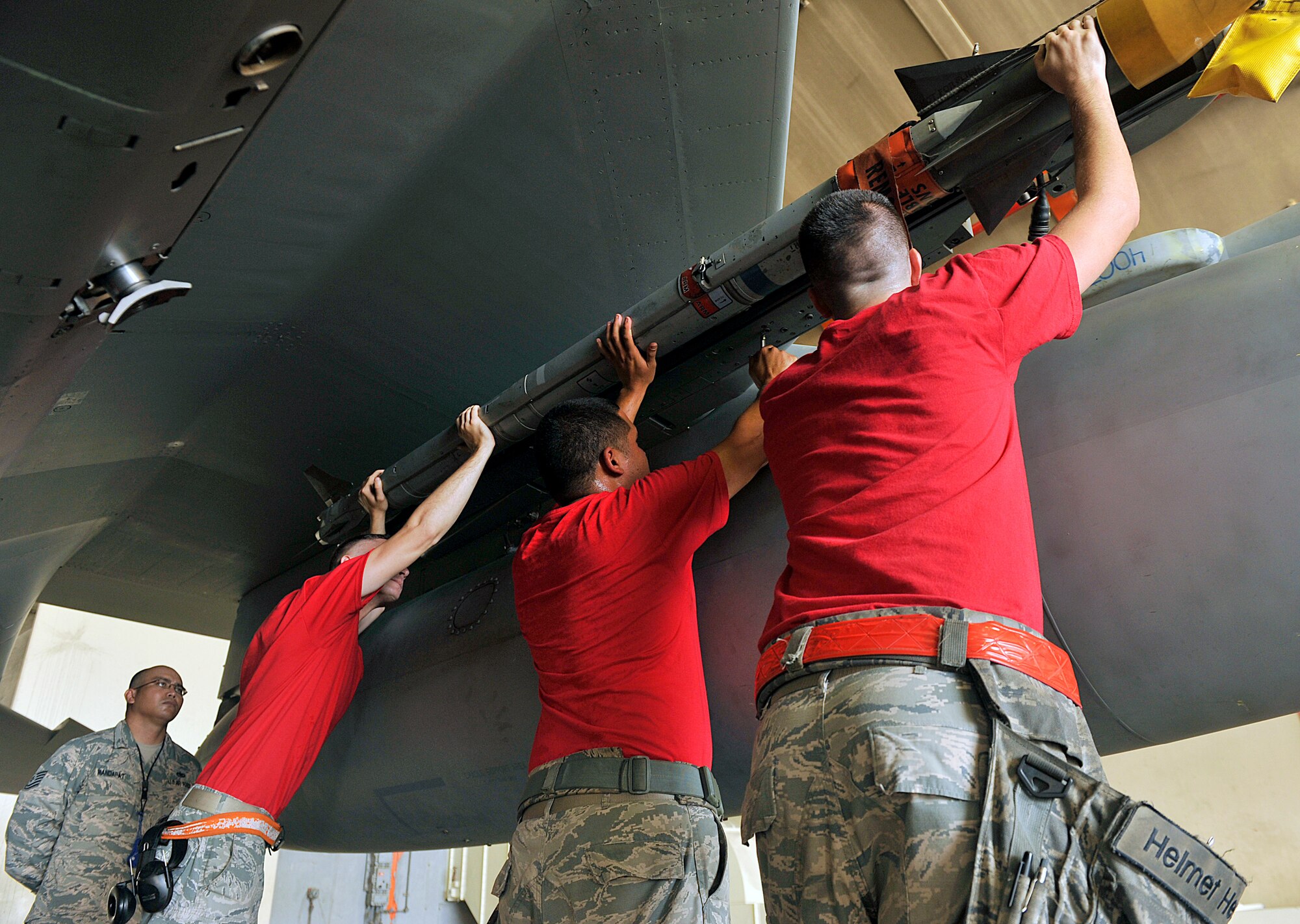 A U.S. Air Force weapons load crew from the 67th Aircraft Maintenance Unit work together to lift an AIM-9L/M Sidewinder Missile onto a U.S. Air Force F-15C Eagle during the second-quarter weapons load competition on Kadena Air Base, Japan, July 17, 2015. This competition tests the team's ability and teamwork to arm F-15s in a fast and safe manner. The 44th and 67th AMUs joined in this friendly competition to see who the fastest weapons load team in the 18th Aircraft Maintenance Squadron is and claim bragging rights for the quarter. (U.S. Air Force photo by Naoto Anazawa)