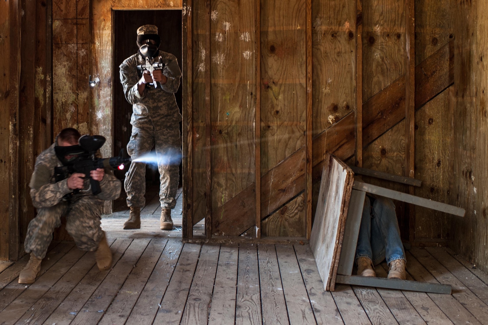 Soldier with U.S. Army Reserve 312th Engineer Company fires M4 rifle paintball gun while opposing force member hides during urban operations training and building clearing procedures, April 18, 2015, at Camp Ripley, Minnesota (U.S. Army/Timothy L. Hale)