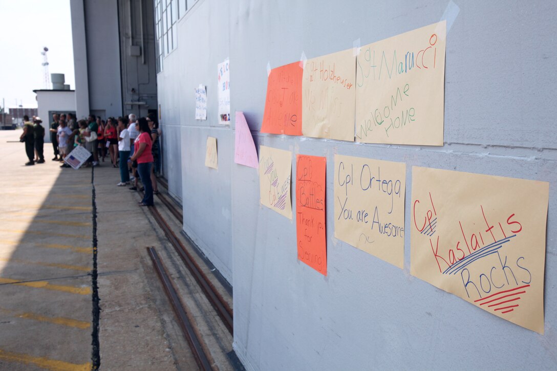 Signs welcoming the service members of Marine Aerial Refueler Transport Squadron 252 hang on the VMGR-252 hangar doors while the families anxiously wait for their loved ones to return to them during a return celebration at Marine Corps Air Station Cherry Point, North Carolina, July 20, 2015. Eighty Marines arrived in VMGR-252’s hangar to meet their families for the first time in half a year, after returning from a deployment in Moron Air Base, Spain, maintaining readiness for crisis response in Africa.