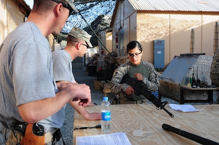 Army Staff Sgt. Ryan L. Pierce, a squad leader for the 3/6 Kansas Cavalry Agribusiness Development Team-III, and Army Sgt. 1st Class Eric Kaltenborn, the security forces platoon sergeant also with the ADT, watch as spur ride candidate Air Force Senior Airman Melissa Hidalgo Mendez, a medic and possibly the first female Kansas Air Guard member to ear spurs, demonstrates her weapon skills with the M-16 rifle during her trek through the spur ride conducted on Forward Operating Base Mehtar Lam, Afghanistan, May 25. Pierce and Kaltenborn are spur holders. The tradition of the spur ride and 'earning the spurs' goes back to the origin of the U.S. Cavalry, with new riders learning the ropes prior to donning the spurs that earmark a cavalryman.