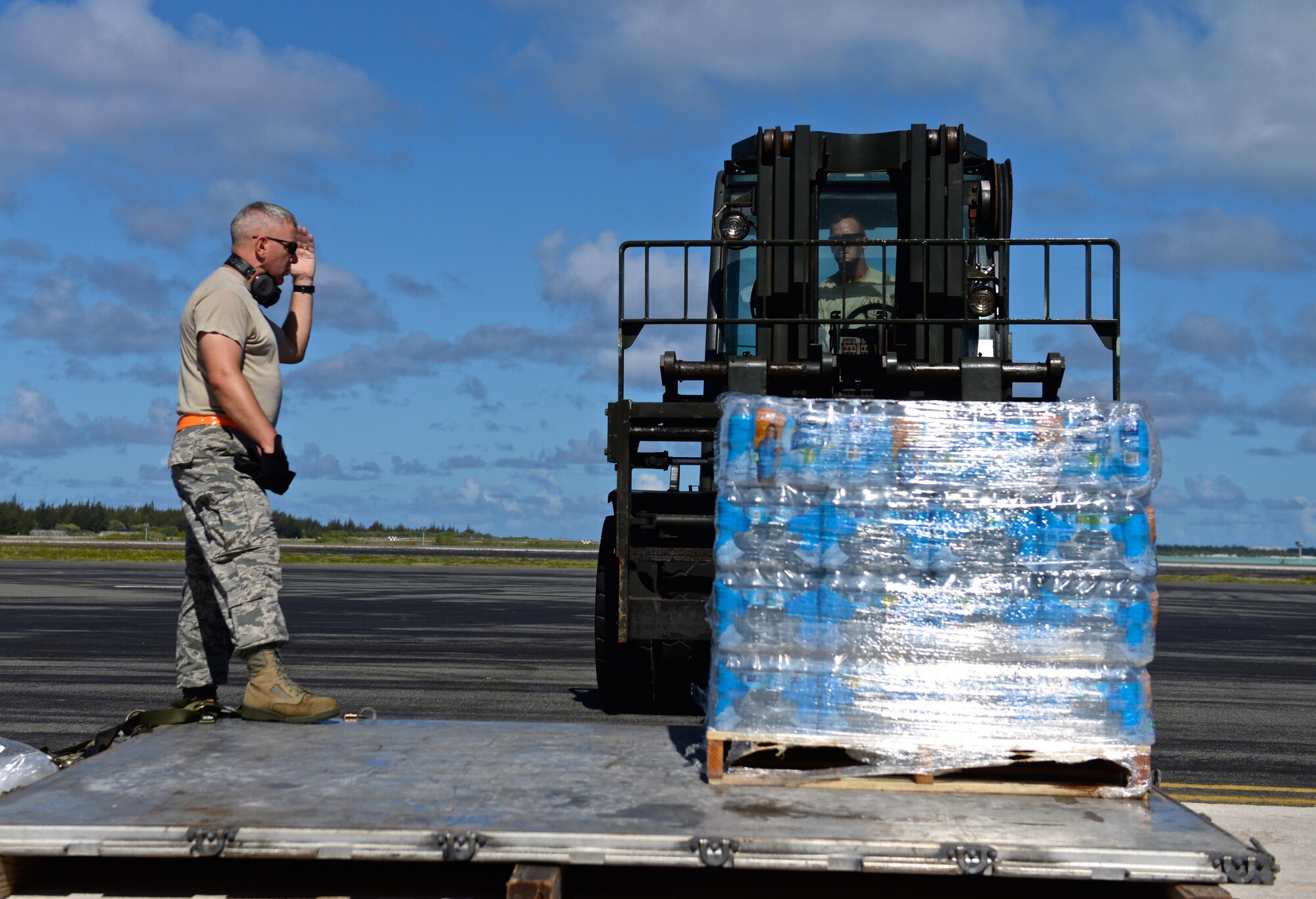 Master Sgt. Iain Morrison, the 36th Contingency Response Group superintendent of operations, plans and programs, guides Tech. Sgt. Randy Walgren, the 36th Mobility Response Squadron NCO in charge of aerial port operations, in moving drinking water rations July 20, 2015, on Wake Island Airfield. The 36th CRG deployed from Andersen Air Force Base, Guam, to assist in airfield storm recovery efforts after the small atoll was evacuated a few days earlier for Typhoon Halola. (U.S. Air Force photo/Senior Airman Alexander W. Riedel) 