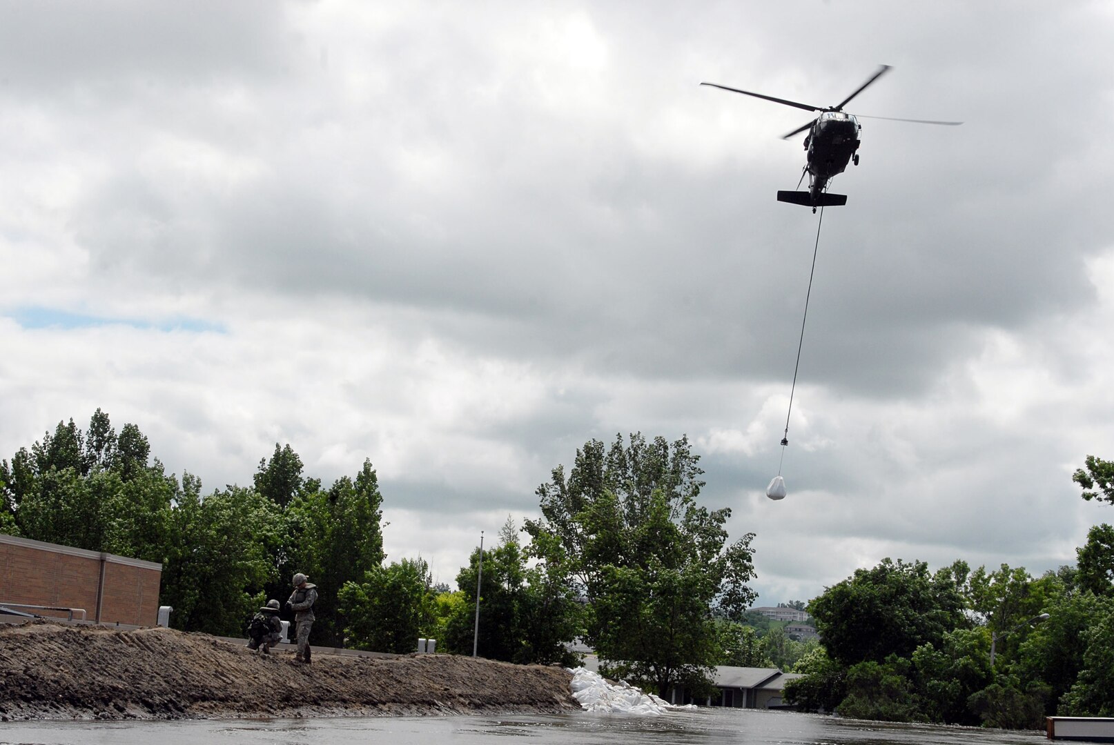 An Army Guard UH-60 Black Hawk prepares to drop one-ton sandbags on a dike to
keep it from deteriorating any further June 27, 2011. The dike is the only
thing holding back the floodwaters in Minot, N.D. from overtaking the
elementary school, which is the only one in the city that remains dry.