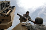 Army Pfc. Michael Forrest, a gunner with the Ohio National Guard's Battery B, 2nd Battalion, 174th Air Defense Artillery Regiment, crouches atop a Humvee to receive a Stinger missile launch tube from his team leader Army Sgt. David Cook while performing Avenger missile reload procedures May 13, 2011. The unit’s Soldiers will operate the Avenger missile system later this year during Operation Clear Skies, which is a mission to protect the airspace over the National Capital Region.