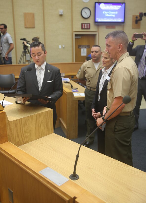 Chris Cate, San Diego councilmember of District 6, presents the Marine Corps Air Station Miramar Single Marine Program 20th Anniversary proclamation to Col. John Farnam, commanding officer of MCAS Miramar during a council meeting at the City Administration Building, San Diego, July 21. The SMP received recognition for contributing more than 300 hours of volunteer effort to the city of San Diego. (U.S. Marine Corps photo by Lance Cpl. Kimberlyn Adams/Released)