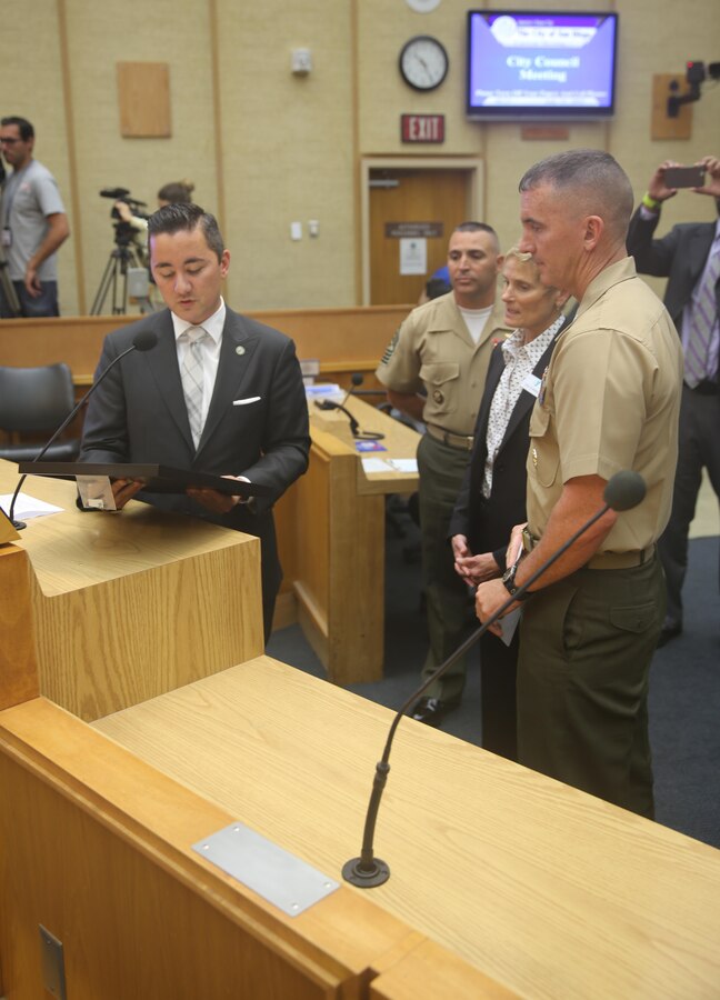 Chris Cate, San Diego councilmember of District 6, presents the Marine Corps Air Station Miramar Single Marine Program 20th Anniversary proclamation to Col. John Farnam, commanding officer of MCAS Miramar during a council meeting at the City Administration Building, San Diego, July 21. The SMP received recognition for contributing more than 300 hours of volunteer effort to the city of San Diego. (U.S. Marine Corps photo by Lance Cpl. Kimberlyn Adams/Released)