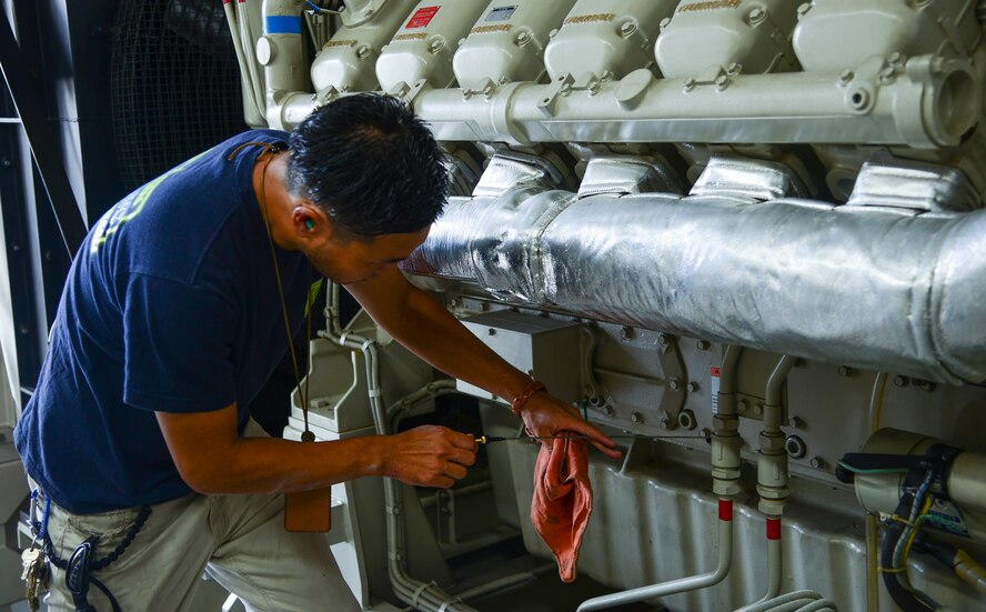 Masanori Okano, 374th Civil Engineer Squadron electrical power production technician, checks the oil level in a generator at Yokota Air Base, Japan, June 30, 2015. During the inspection, power production members checked the water pressure, coolant temperature, oil pressure and ensured the generator remained fully operational. (U.S. Air Force photo by Senior Airman David Owsianka/Released)
