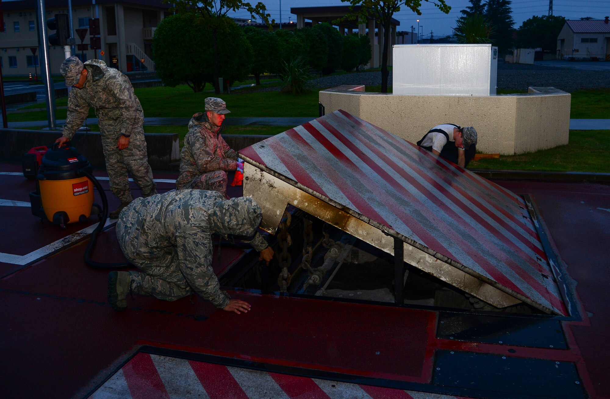 Airmen with the 374th Civil Engineer Squadron electrical power production unit clean a anti-vehicle barrier at Yokota Air Base, Japan, July 23, 2015. The system is used as an extra line of defense, preventing unauthorized vehicles from entering the base. (U.S. Air Force photo by Senior Airman David Owsianka/Released)
