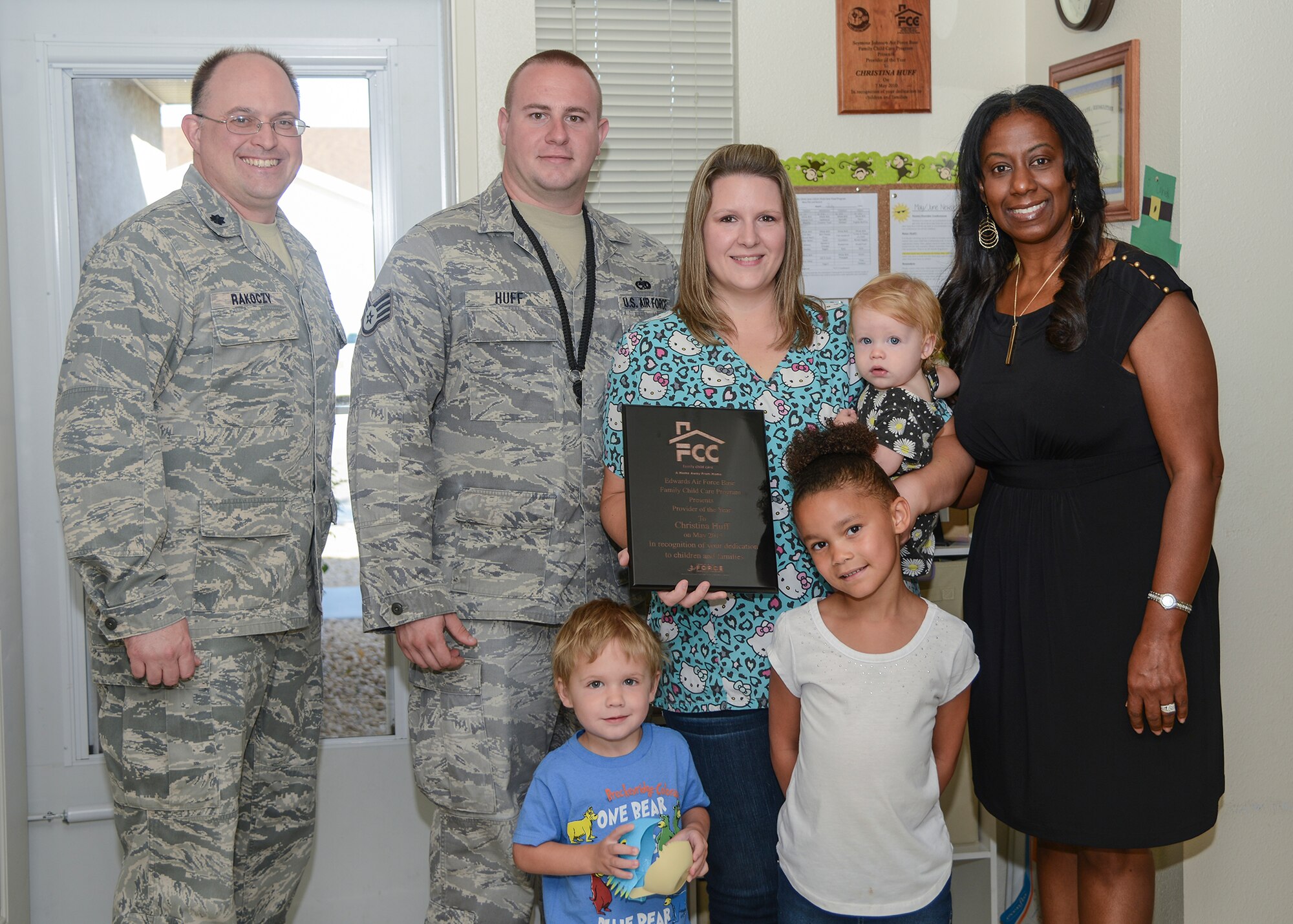 Lt. Col. Michael Rakoczy (far left), 412th Mission Support Group deputy commander, and Latasha Bushrod (far right), Edwards Family Child Care coordinator, presented Christina Huff with the 2015 Family Child Care Provider of the Year plaque in her home July 22. Huff is joined by her husband, Staff Sgt. Thomas Huff and several of the children in the program. (U.S. Air Force photo by Rebecca Amber)