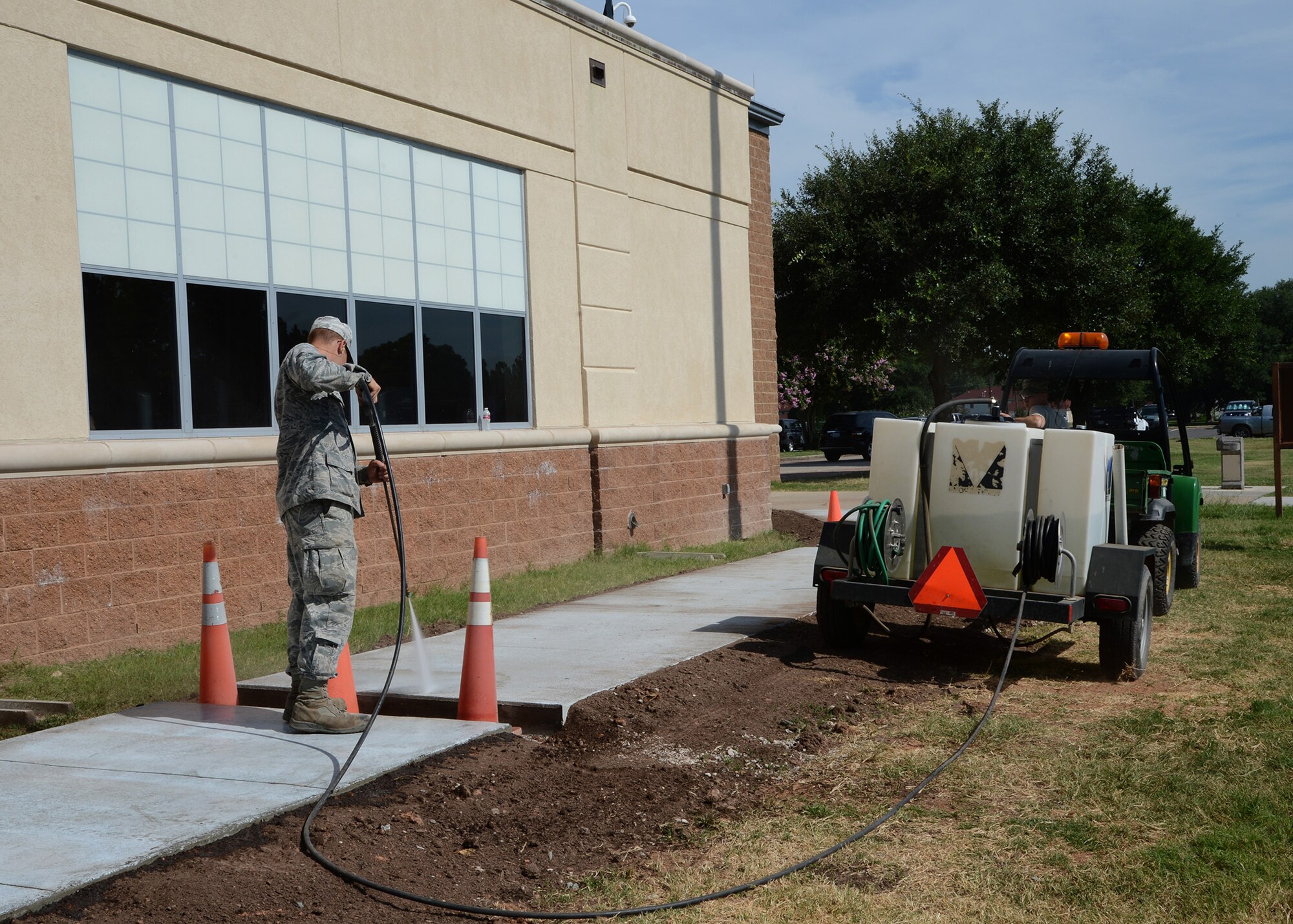 2nd Civil Engineer Squadron pavements and equipment Airmen clean off a newly installed sidewalk at the Senior Airman Bryan Bell Fitness Center on Barksdale Air Force Base, La., July 21, 2015. Eight Airmen worked 45 days to install the nearly 400 foot sidewalk. (U.S. Air Force photo/Senior Airman Joseph A. Pagán Jr.)