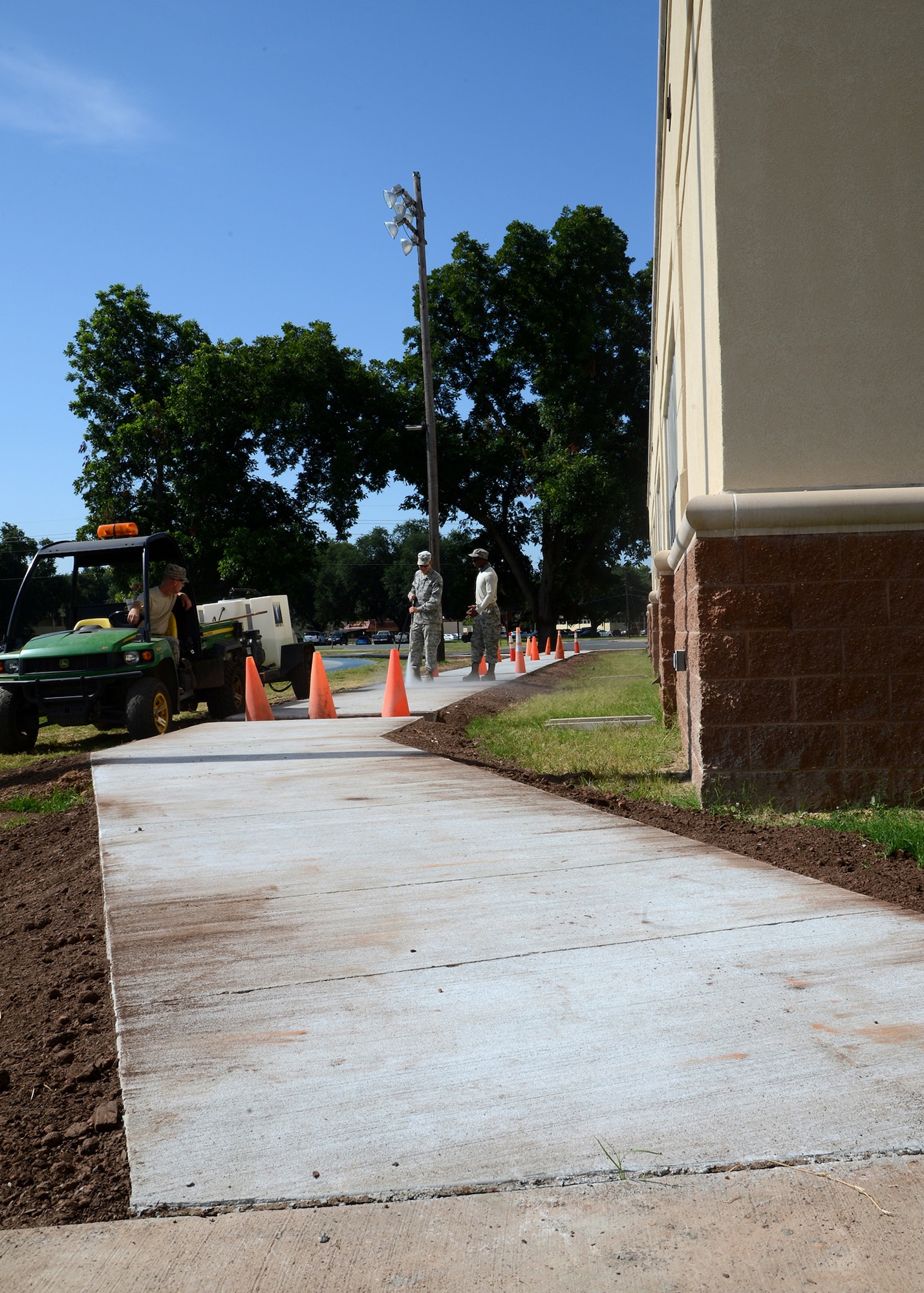 Airmen from the 2nd Civil Engineer Squadron pavements and equipment flight clean off a newly installed sidewalk at the Senior Airman Bryan Bell Fitness Center on Barksdale Air Force Base, La., July 21, 2015. The sidewalk took three weeks to complete and will provide Airmen safer access to the fitness center. (U.S. Air Force photo/Senior Airman Joseph A. Pagán Jr.)
