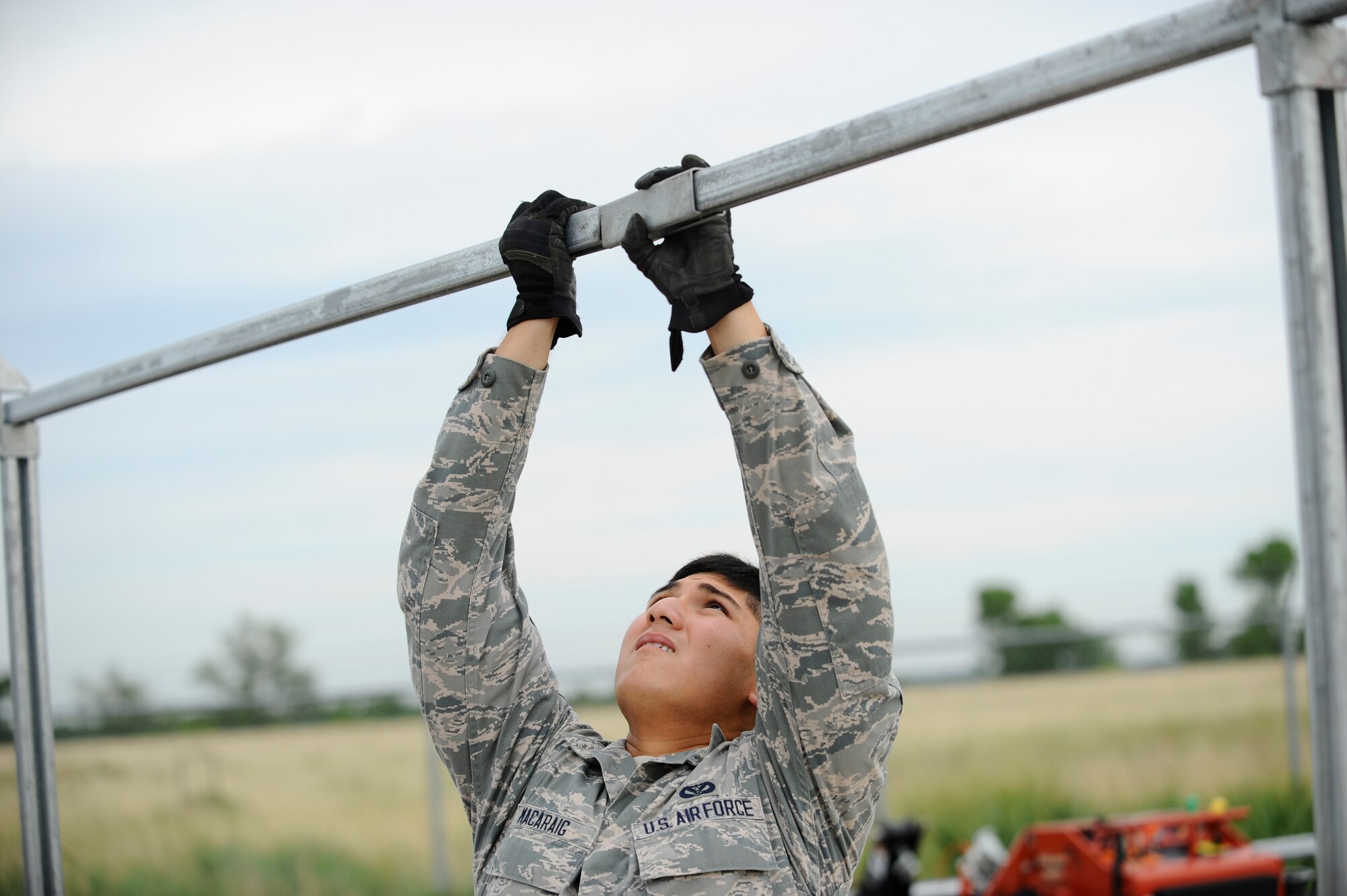 Senior Airman Michael Macaraig, 22nd Civil Engineer Squadron horizontal pavements shop heavy equipment operator, connects two top rails on a fence, July 22, 2015, at McConnell Air Force Base, Kan. The Airmen, known as “Dirt Boyz” are known to work in the dirt and mud while working on a variety of different projects, including setting up perimeter fences, laying concrete and other outdoor tasks. (U.S. Air Force photo by Senior Airman Victor J. Caputo)