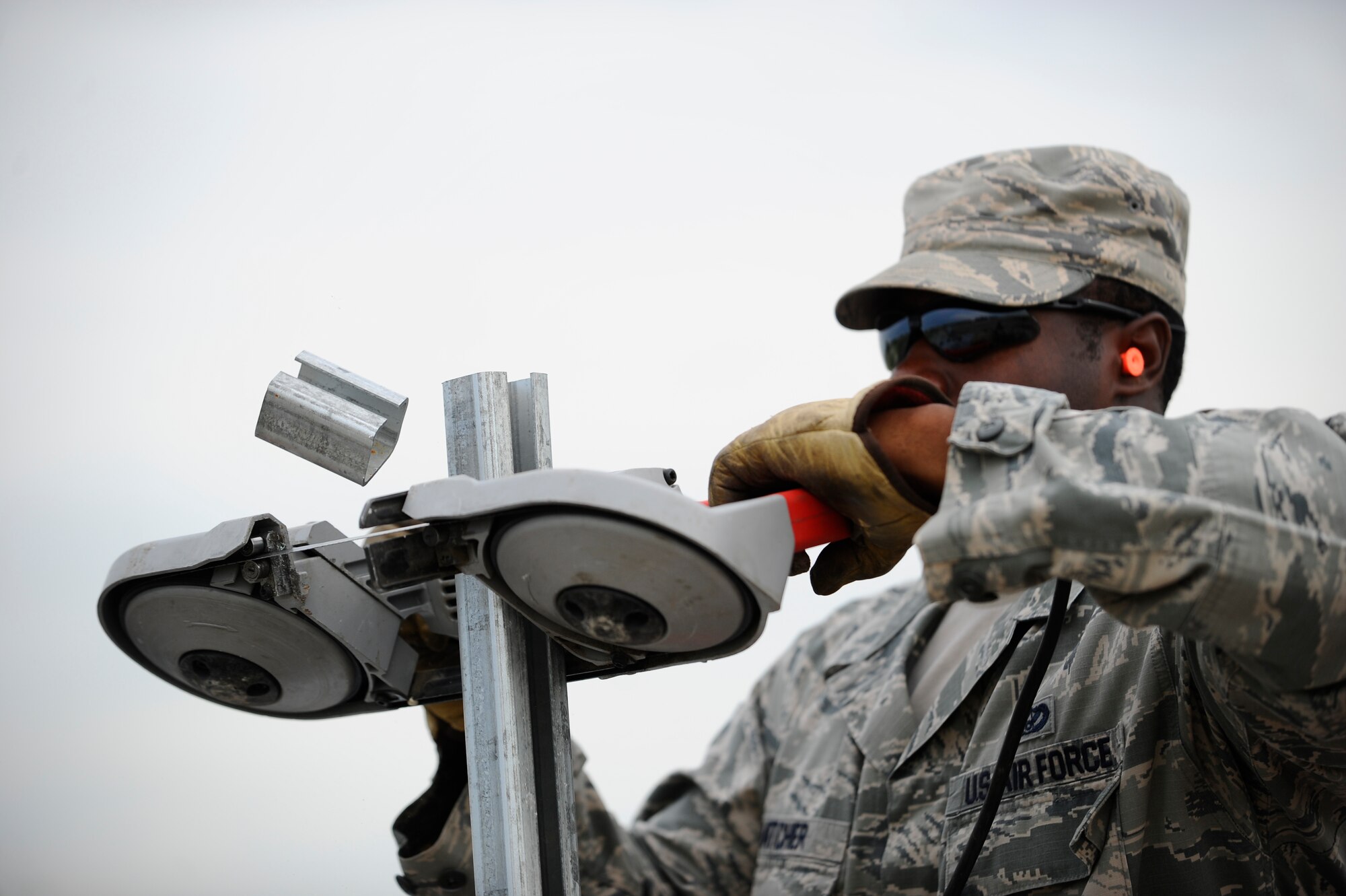 Senior Airman Willie Hatcher, 22nd Civil Engineer Squadron horizontal pavements shop heavy equipment operator, cuts a fence post, July 22, 2015, at McConnell Air Force Base, Kan. Security is a top priority on base, so the “Dirt Boyz” were tasked to erect a new fence to help keep the people and resources of Team McConnell safe. (U.S. Air Force photo by Senior Airman Victor J. Caputo) 