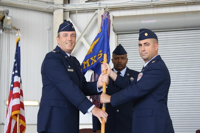Colonel Brian Peters, 437th Maintenance Group commander, passes the guidon to Maj. Robert Ryder, the new 437th Aircraft Maintenance Squadron commander during an assumption of command ceremony held at Joint Base Charleston, S.C., July 22, 2015. Ryder comes to JB Charleston from MacDill Air Force Base, Fla., where he was the 6th Aircraft Maintenance Squadron commander. Lt. Col. Adam DiGerolamo, the former 437th AMXS commander departed JB Charleston in June 2015 and is now the 379th Expeditionary Aircraft Maintenance Squadron commander at Al Udeid Air Base. (Courtesy photo / 437th Aircraft Maintenance Squadron) 
