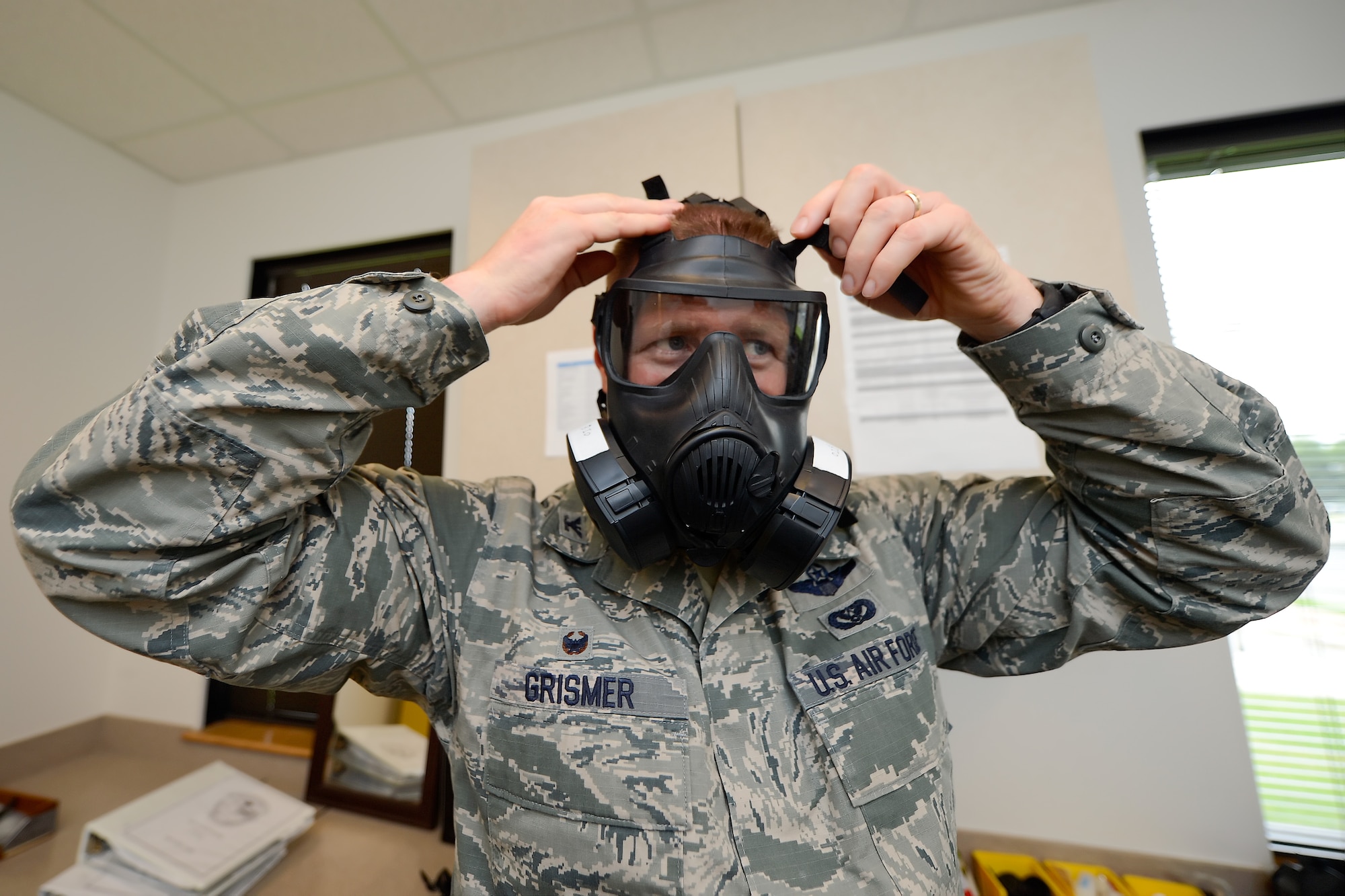 Col. Michael Grismer, 436th Airlift Wing commander, adjusts the tension on straps of a M50 joint service protective gas mask during a visit to the 436th Aerospace Medicine Squadron Biological Environmental Flight July 17, 2015, at Dover Air Force Base, Del. Grismer donned the gas mask and did a fit and function test while learning about the mission of the flight during his visit. (U.S. Air Force photo/Greg L. Davis)